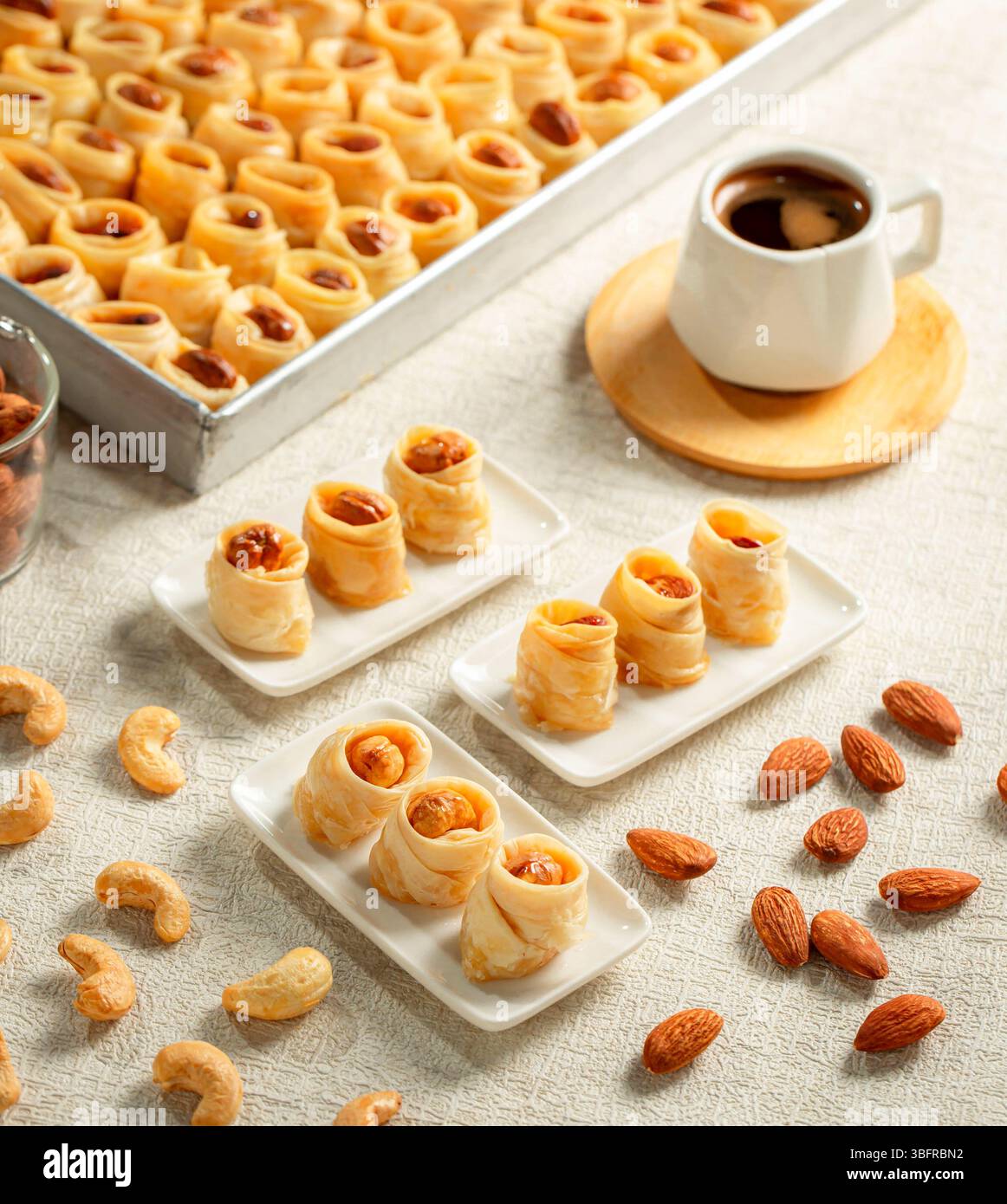 Verschiedene osmanische arabische Desserts mit gemischten Nussbrötchen (Mandel, Pistazien, Cashew), serviert mit Kaffee auf weißem Hintergrund Stockfoto