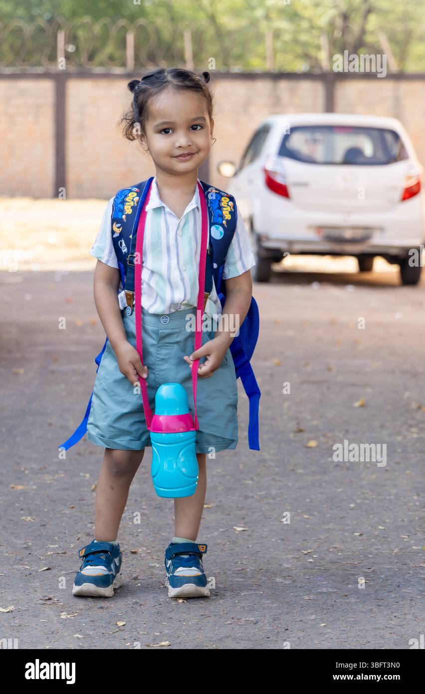 indisches Kind süßer Ausdruck mit Betteln und Wasserflasche für den ersten Schultag an sonnigem Tag Stockfoto