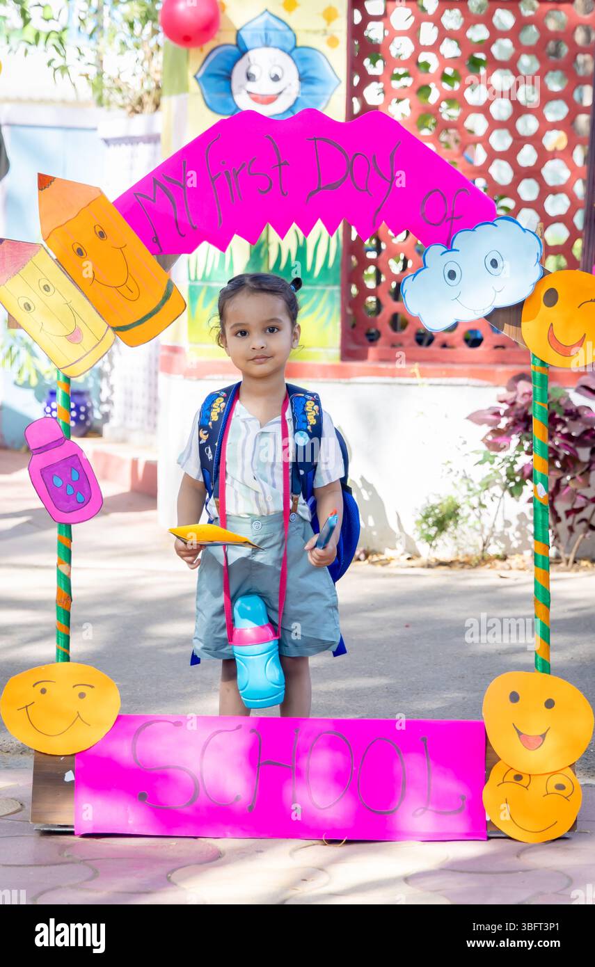 Entzückendes indisches Vorschulkind mit Fotostand am ersten Schultag im Freien Stockfoto