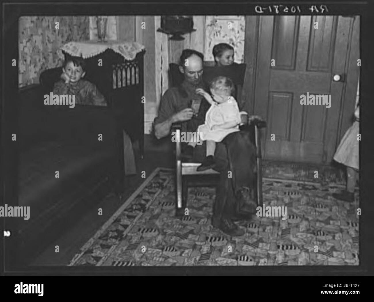 Um 19:40 Uhr ist Tip Estes, ein Angestellter, bei seinem jüngsten Kind. Nach dem Abendessen bleibt die Familie bis zum Schlafengehen sitzen, ohne dass im Haus Lesematerial vorhanden ist. Stockfoto