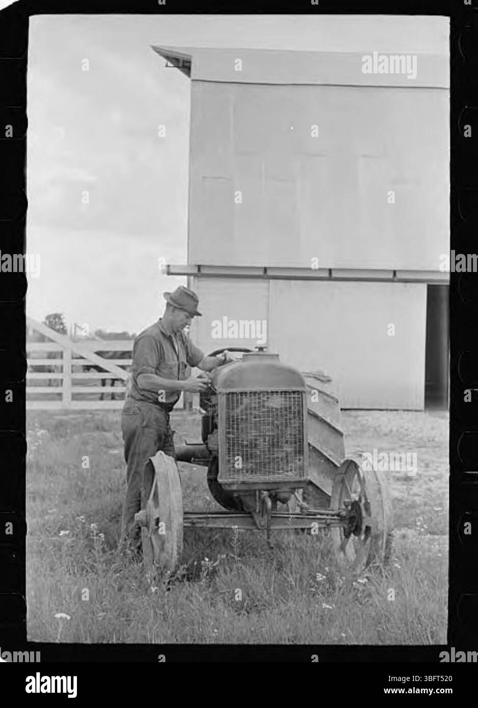 Landwirte in der Loogootee-Einheit werden beim Ölen eines Traktors gesehen, was Teil der Wartung der landwirtschaftlichen Ausrüstung ist, die für landwirtschaftliche Arbeiten erforderlich ist. Diese Aufgabe ist entscheidend, um die Maschinen während der landwirtschaftlichen Tätigkeit betriebsbereit zu halten. Stockfoto