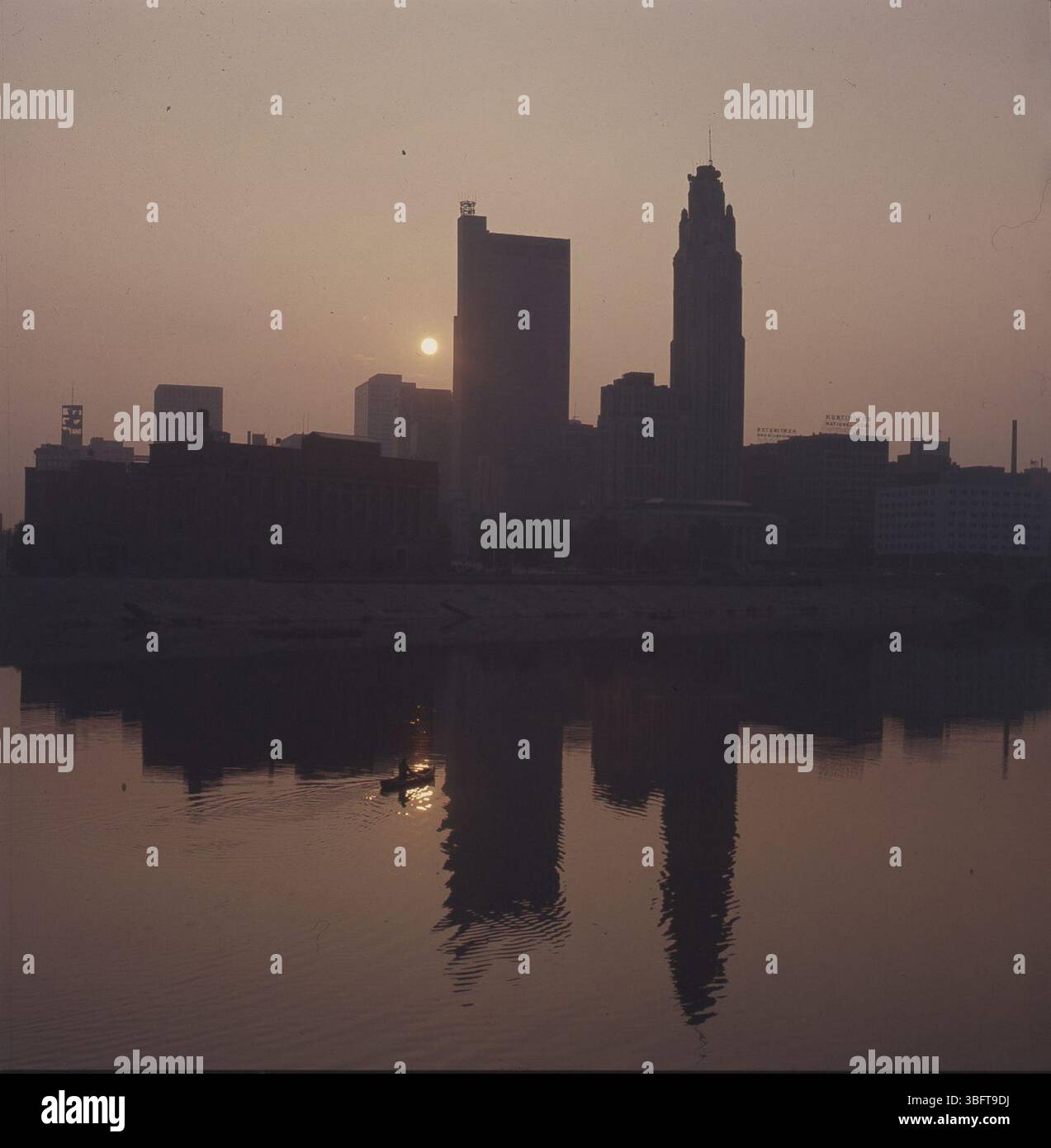 Ein ruhiger Blick auf die Skyline von Columbus vom Scioto aus, mit einem Kanu, das auf dem Wasser gleitet. Das frühe Licht beleuchtet die Gebäude der Innenstadt und zeigt die lebhafte Atmosphäre der Stadt. Stockfoto