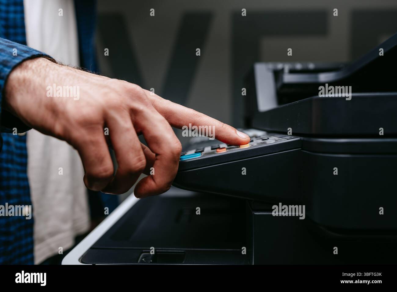 Die Person verwendet einen Multifunktionsdrucker, um die Kopier- oder Scanfunktionen in einem Büro während der Tageslichtstunden zu bedienen Stockfoto