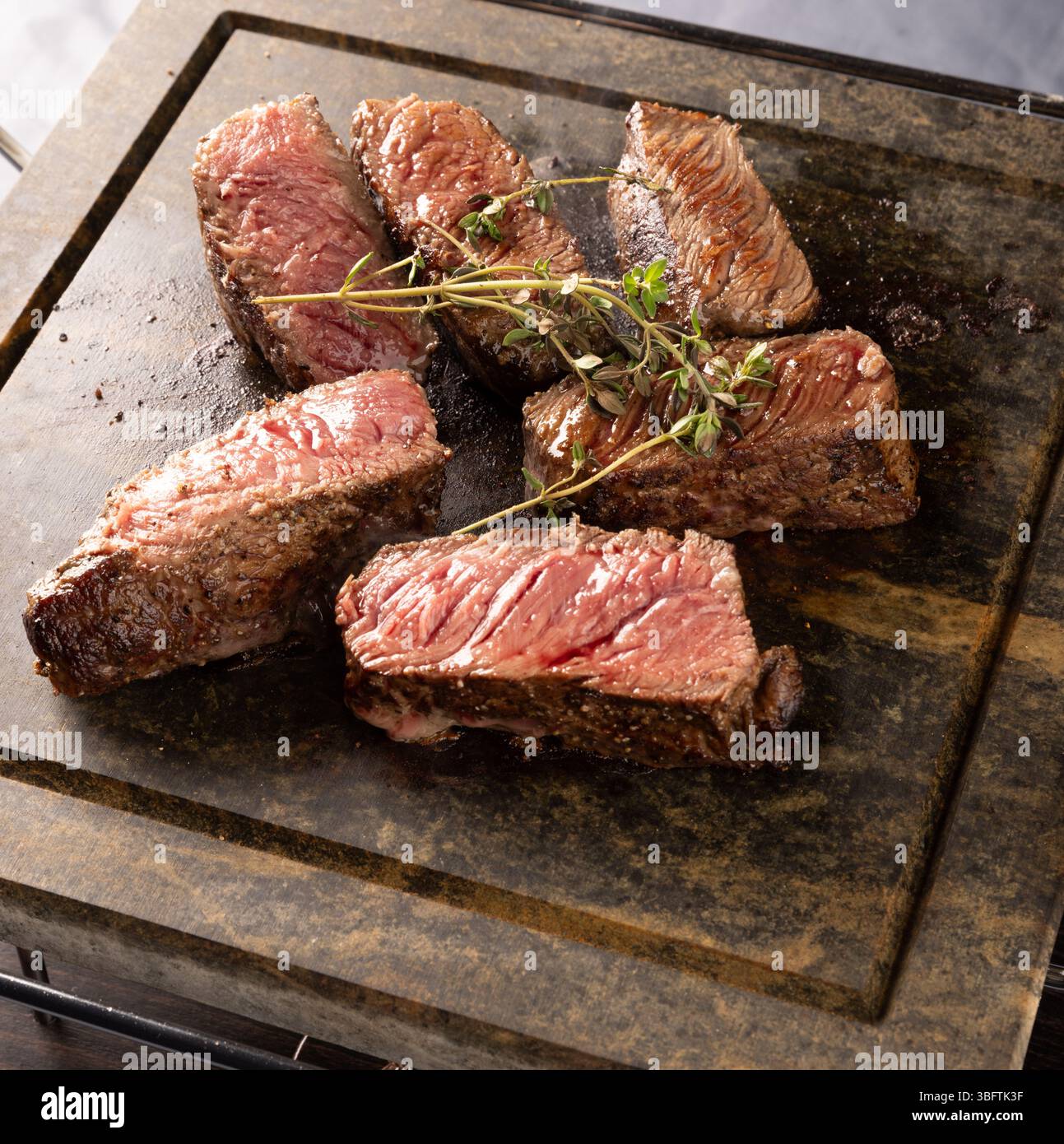 Nahaufnahme saftiger gegrillter Steaks mit frischen Kräutern Stockfoto