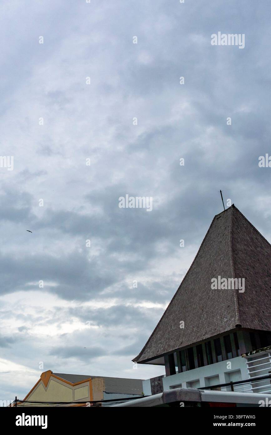 Gebäude mit spitzem Dach sind vor einem bewölkten Himmel zu sehen. Das Gebäude ist braun und weiß Stockfoto