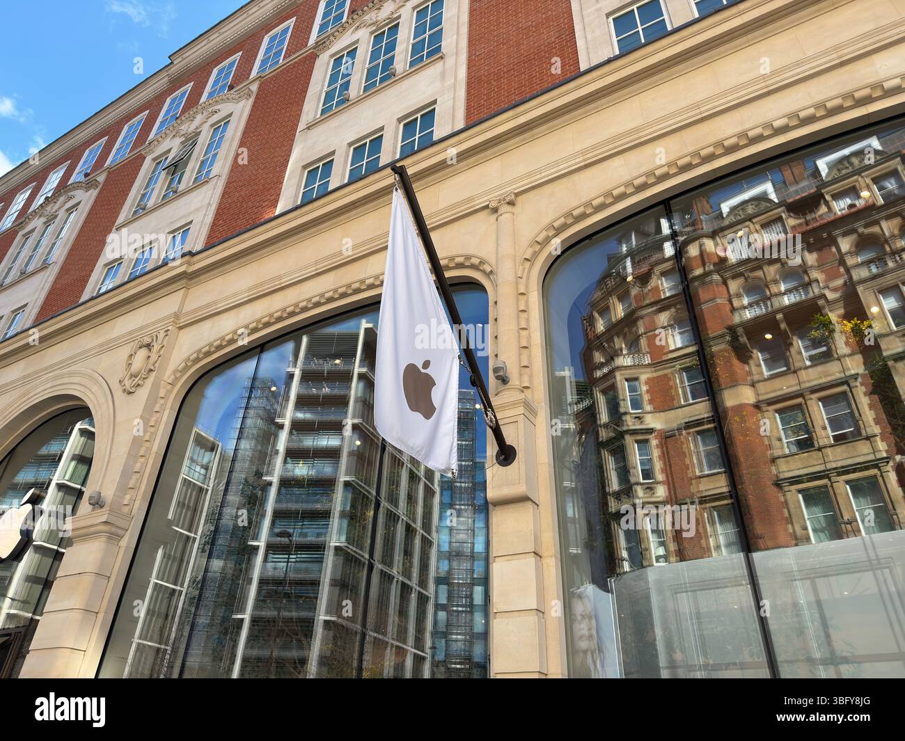 LONDON, ENGLAND – 16. MÄRZ 2025: Die Fassade des Apple Store in Knightsbridge, London, mit der Flagge des Apple-Logos, die die umliegenden Gebäude reflektiert. - Smartphone-aufgenommenes Stockfoto