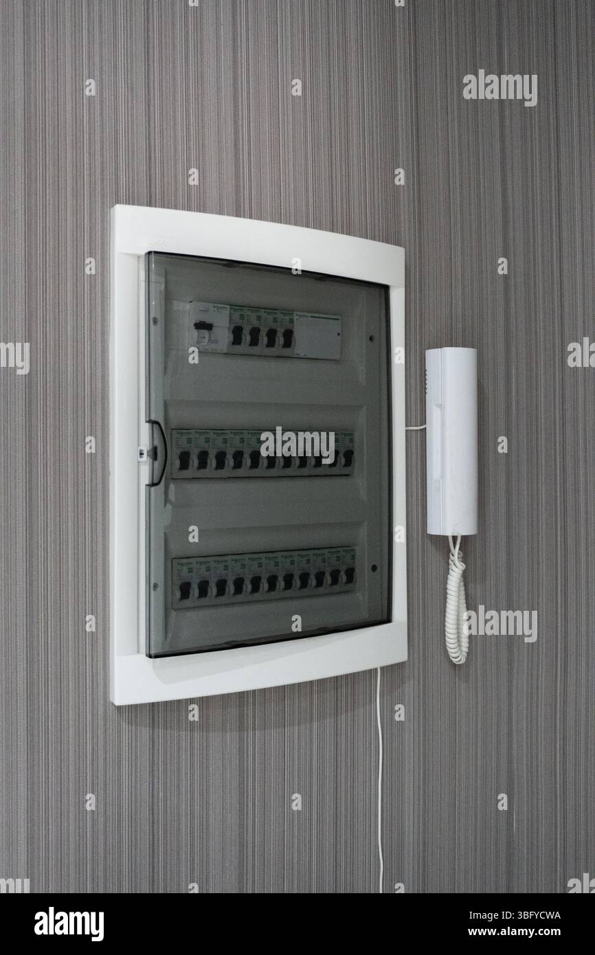 Nahaufnahme einer modernen elektrischen Verbrauchereinheit oder eines Sicherungskastens mit einer Reihe weißer Schneider-Leistungsschalter mit schwarzen Schaltern Stockfoto