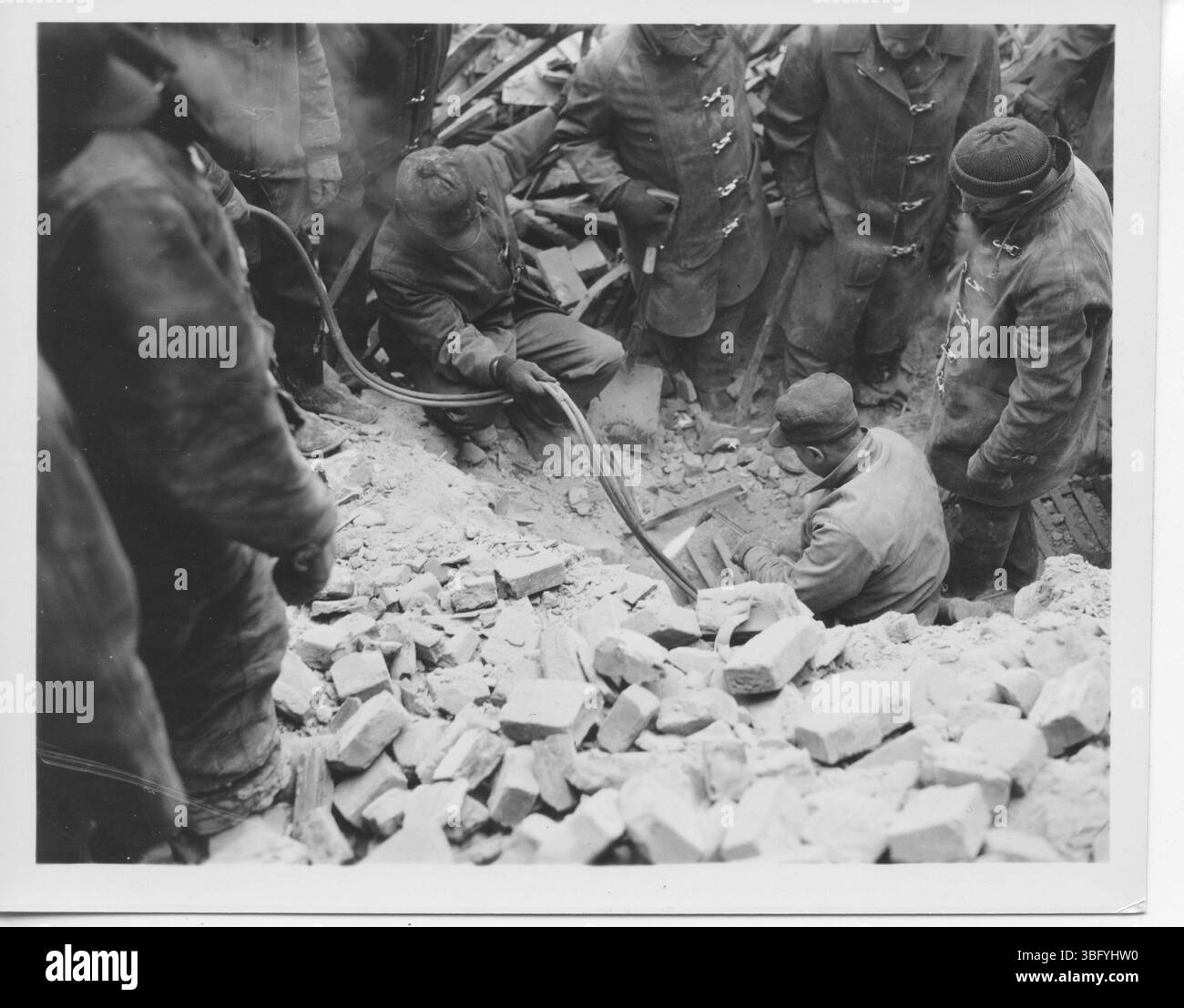 Fotos dokumentieren den verheerenden Brand in der Oddfellows Hall am 19. Februar 1936, als eine Rückwand während der Brandbekämpfung einstürzte. Fünf Feuerwehrleute starben, darunter Herbert Harrington und Otto Ignatze, während andere verletzt wurden. Das Feuer begann am Ofen im vierstöckigen Gebäude, das 1868 errichtet wurde. Der tragische Zusammenbruch verdeutlichte die Gefahr von verfallenem Mörtel und führte zu Änderungen der Löschprotokolle. Stockfoto