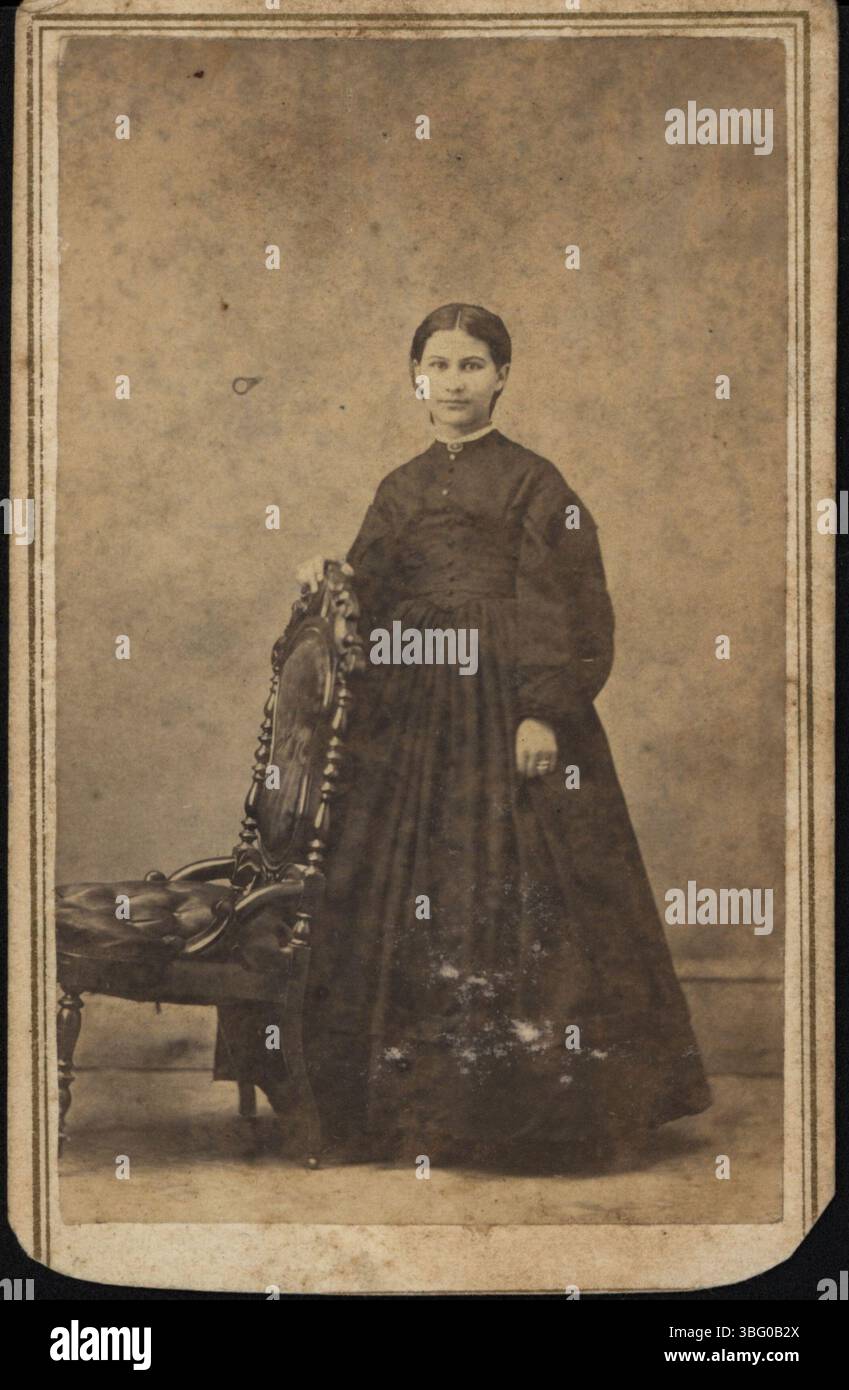 Dieses Foto aus den 1960er Jahren zeigt eine Frau in einem schlichten schwarzen Kleid. Das Bild wurde von Elliott und Heyl aufgenommen und fängt den Stil des Jahrzehnts mit klaren Linien und dezenter Eleganz ein. Stockfoto