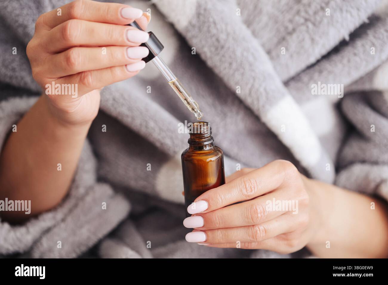 Öffnen der kosmetischen Pipettenflasche. Hautserumtropfer in weiblichen Händen. Natürliches Schönheitselixier in Bernsteinglas. Selfcare und Wellness-Ritual. Stockfoto