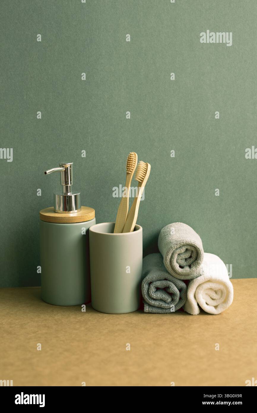 Seife, Shampoo-Flasche und Baumwollhandtücher, Zahnbürste auf braunem Regal. Grüner Wandhintergrund. Badezimmerausstattung Stockfoto