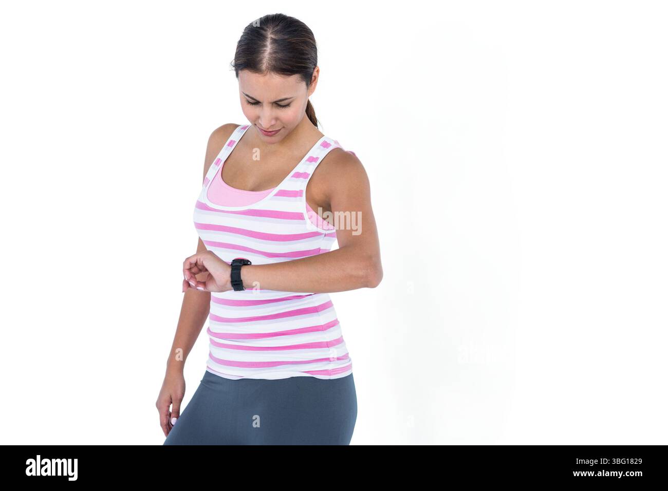 Frau, die vor weißem Hintergrund steht und Fitness-Tracker am linken Handgelenk im Studio überprüft Stockfoto