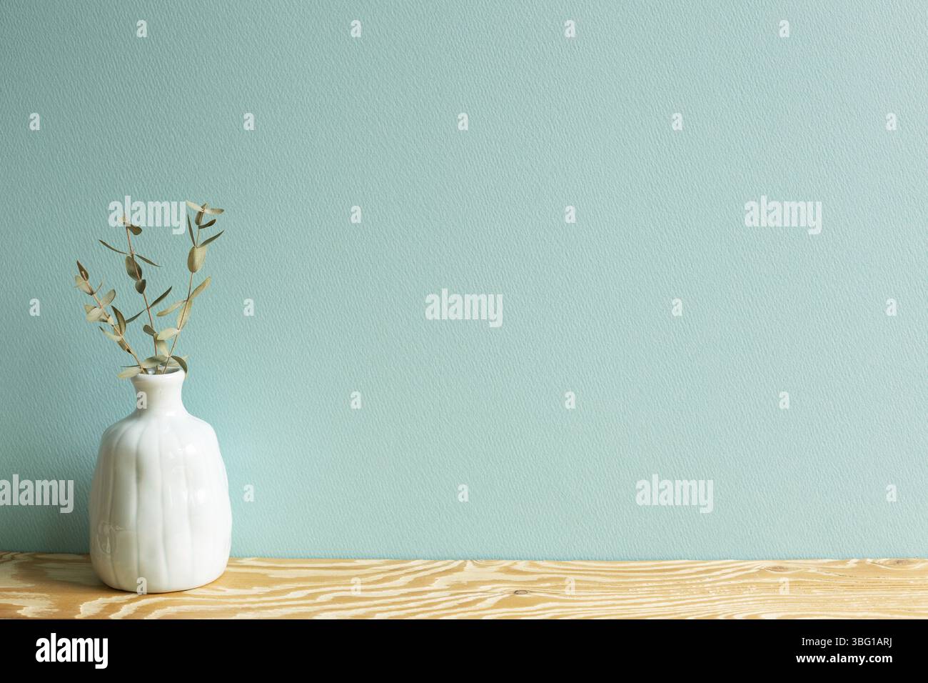 Vase aus Eukalyptusblättern auf Holztisch mit grünem Hintergrund Stockfoto