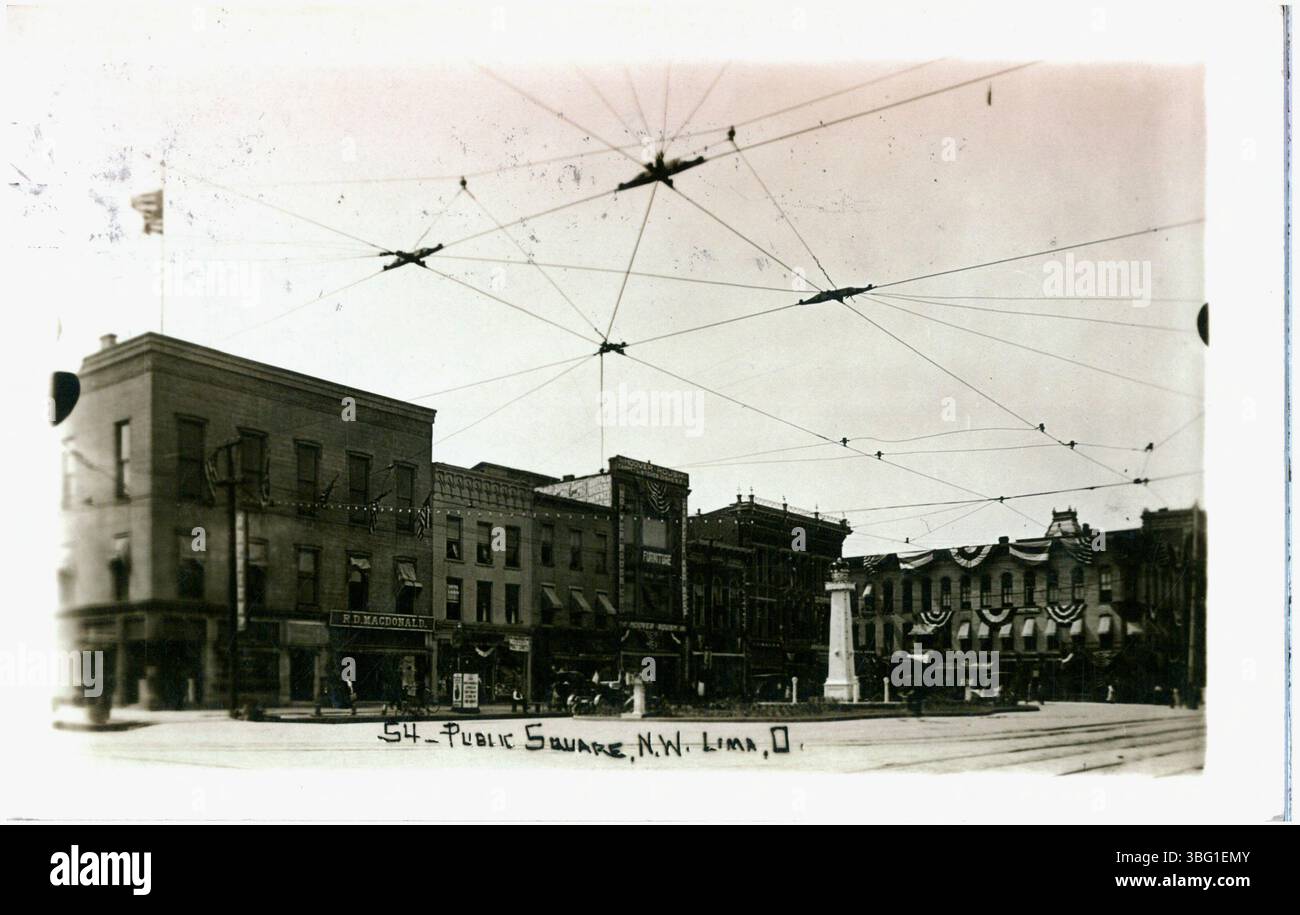 Dieses Schwarzweiß-Foto aus dem Jahr 1910 zeigt den Public Square in Lima, Ohio, mit Blick nach Nordwesten. Das Bild zeigt elektrische Leitungen für die Überlandbahn und identifiziert R. D. McDonald und Hover House Furniture. Auf dem Platz ist eine grüne Insel zu sehen. Stockfoto