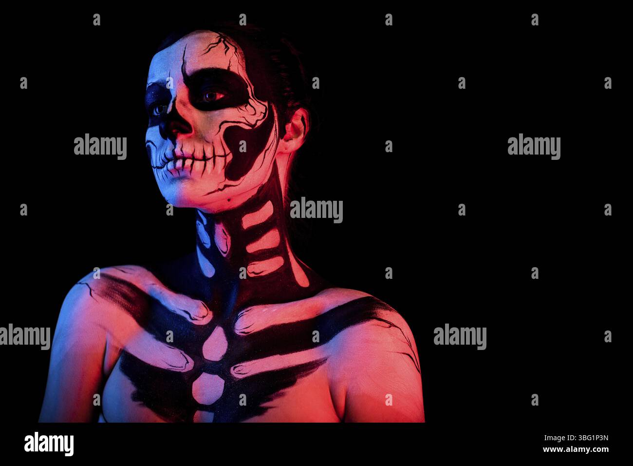 Isoliert auf Schwarz, Nahaufnahme, rot und blau getönt, attraktive junge brünette weiße Frau mit Schädelkörperkunst, graue Augen, Blick links Stockfoto