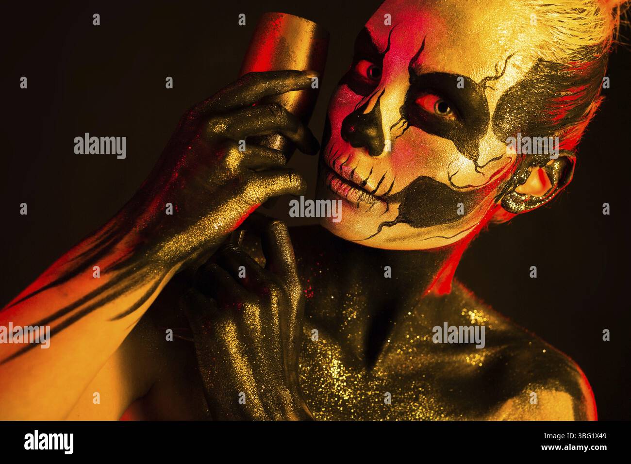 Isoliert auf Schwarz, Nahaufnahme Bild, rot und gelb, schöne junge blonde weiße Frau mit Schädelkörperkunst mit Weinglas in der Hand, graues Auge Stockfoto