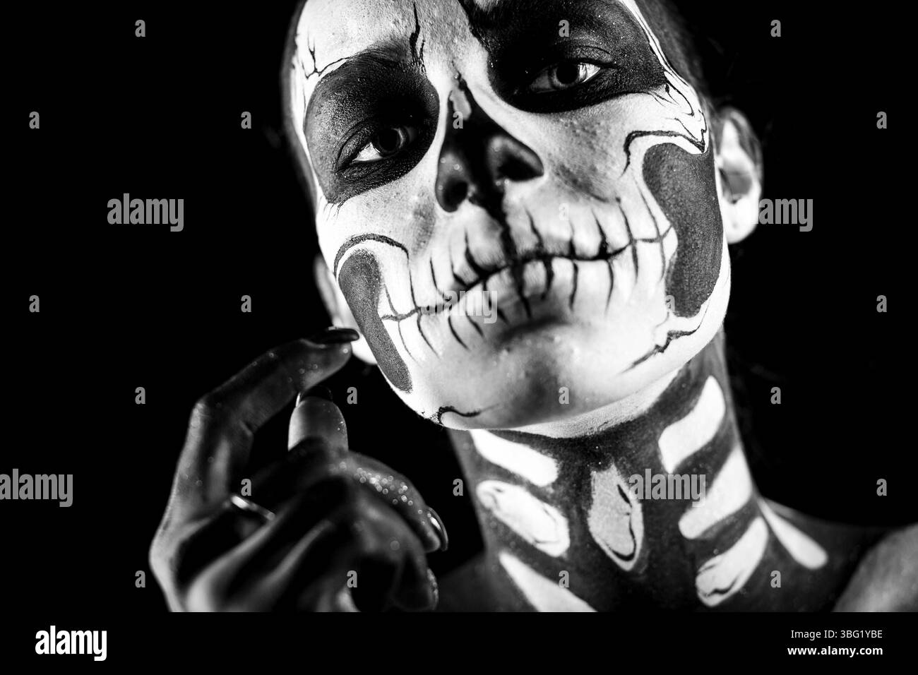 Isoliert auf Schwarz, Nahaufnahme, attraktive junge brünette weiße Frau mit Schädelkörperkunst, grauen Augen, schamem Blick, Blick in die Kamera, Hand in der Nähe Stockfoto