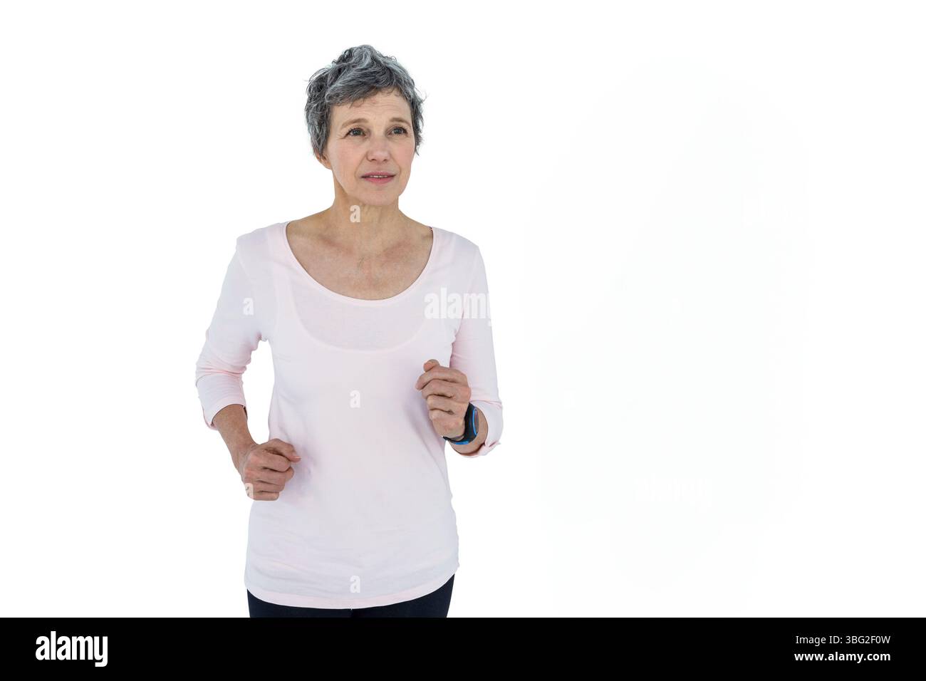 Ältere Frau, die vor Ort joggt, mit hellrosa Oberteil, Leggings, Fitness-Tracker im Studio Stockfoto