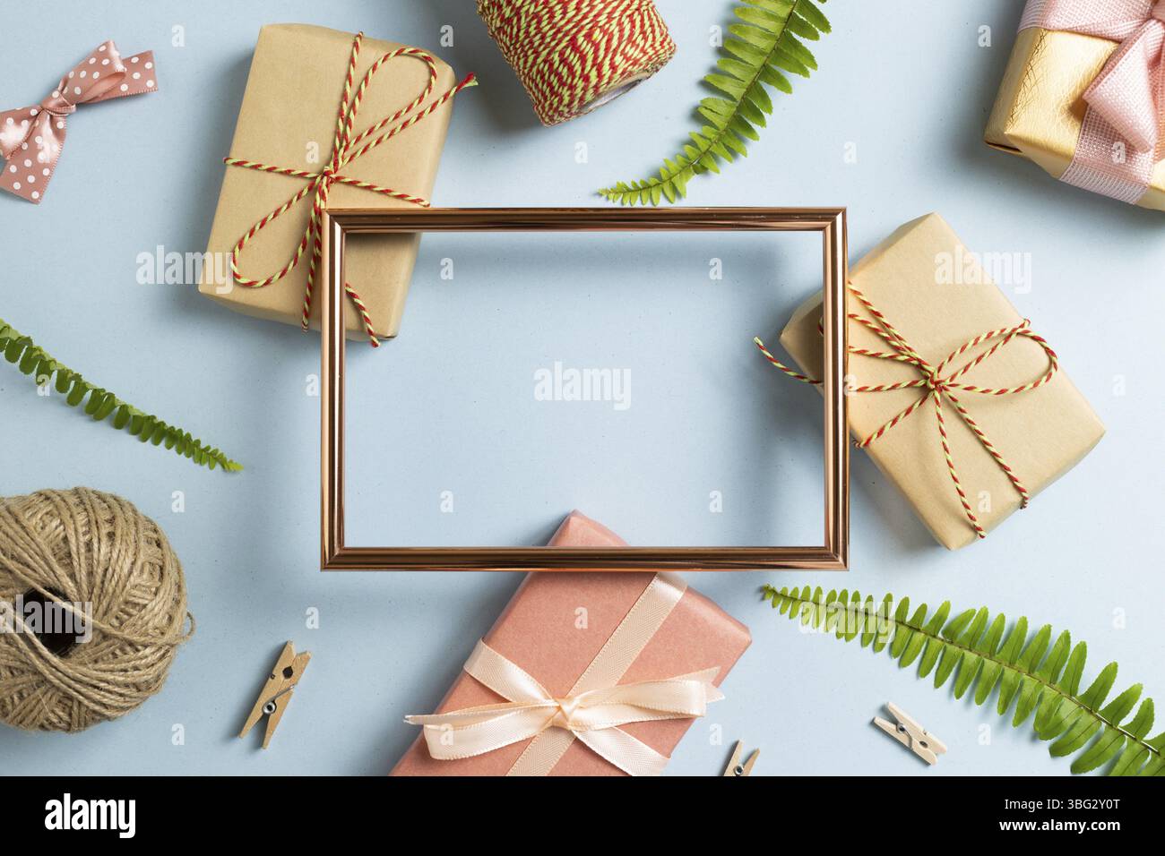 Geschenkverpackung. Leerer Fotorahmen mit Geschenkschachteln auf himmelblauem Hintergrund. Draufsicht, Kopierraum Stockfoto