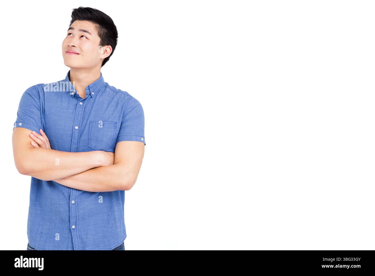 Chinesische männliche Standarme gefaltet, Kopf nach oben und links vor dem Hintergrund des Studios, Kopierraum Stockfoto