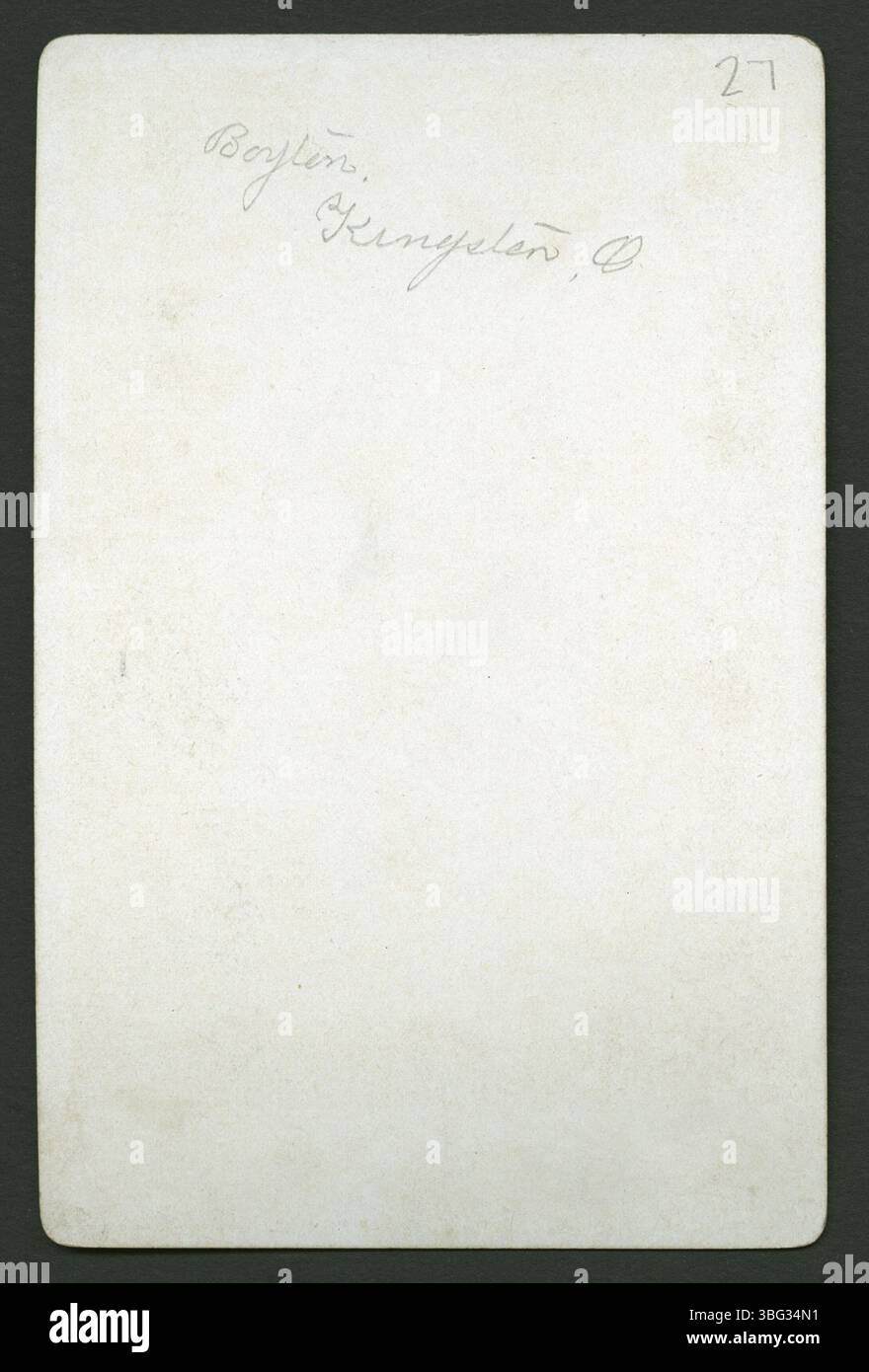 Ein durchgehendes Studio-Porträt eines Kleinkindes in einem langen weißen Kleid mit Rüschenkragen, das auf gemusterten Vorhängen sitzt. Das Foto wurde vom Boynton Studio in Kingston, Ohio, aufgenommen. Stockfoto