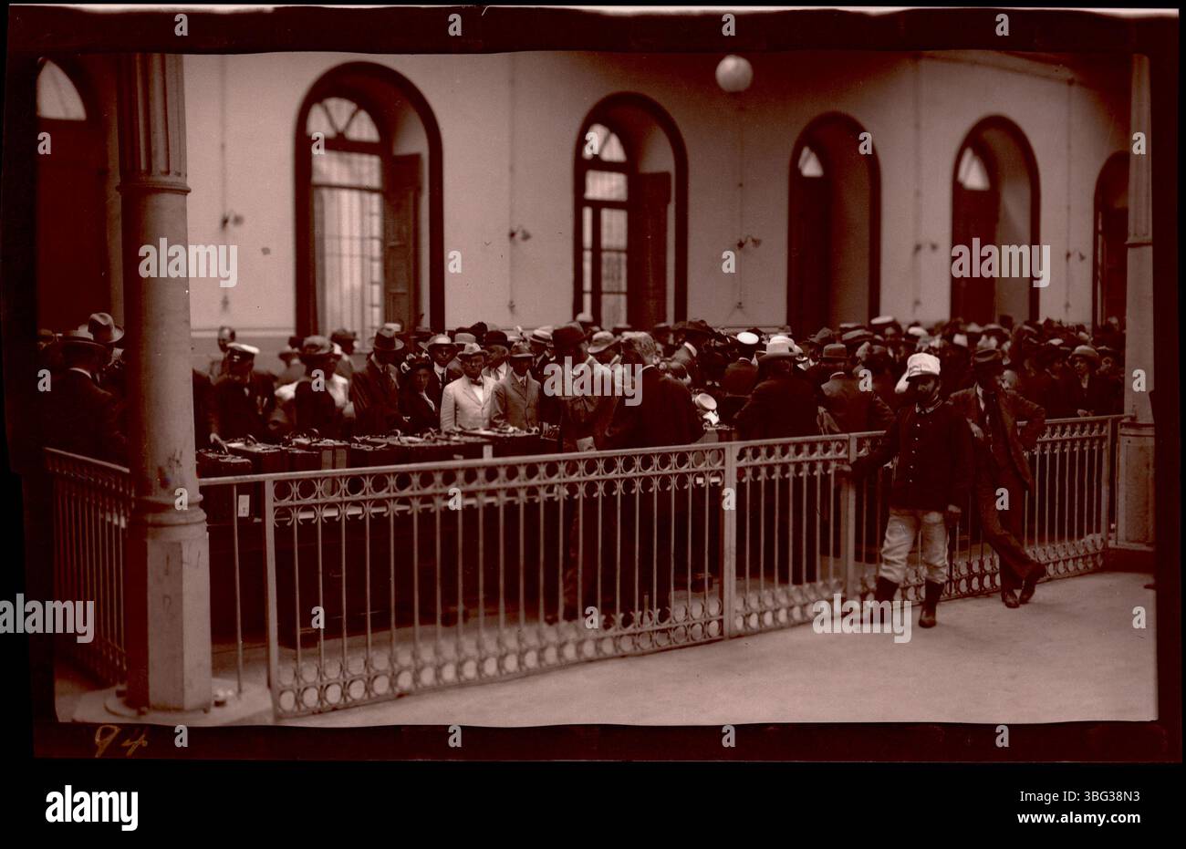 Die Arrases machten 1913 ein Foto von Passagieren, die sich während ihrer Europatour im Palast der Immacolatella, dem Zollhaus in Neapel, Italien, anschlangen. Das Foto zeigt Passagiere mit ihrem Gepäck, wie lokale Beamte beobachten. Stockfoto