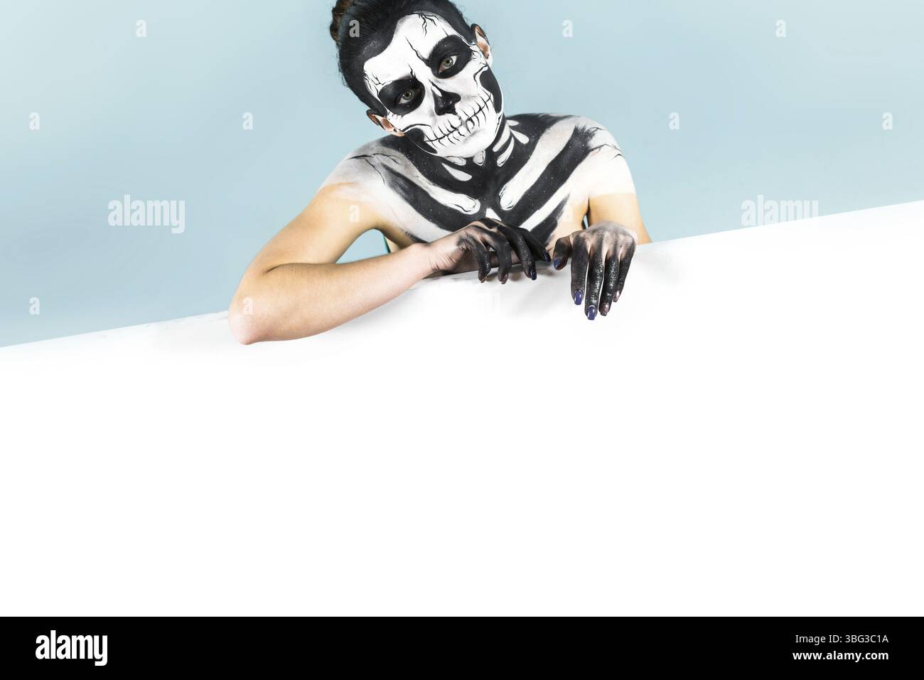 Isoliert auf blauem, Nahaufnahme Bild, junge brünette kaukasierin attraktive Frau mit Schädelkörperkunst hält Megaphon, weit geöffnete graue Augen, vertraut auf die Stockfoto