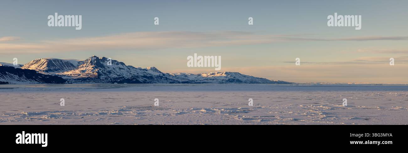 Gefrorenes Meer und schneebedeckte Berge auf Disko Island, Grönland, im weichen polaren Abendlicht während des arktischen Winters. Stockfoto
