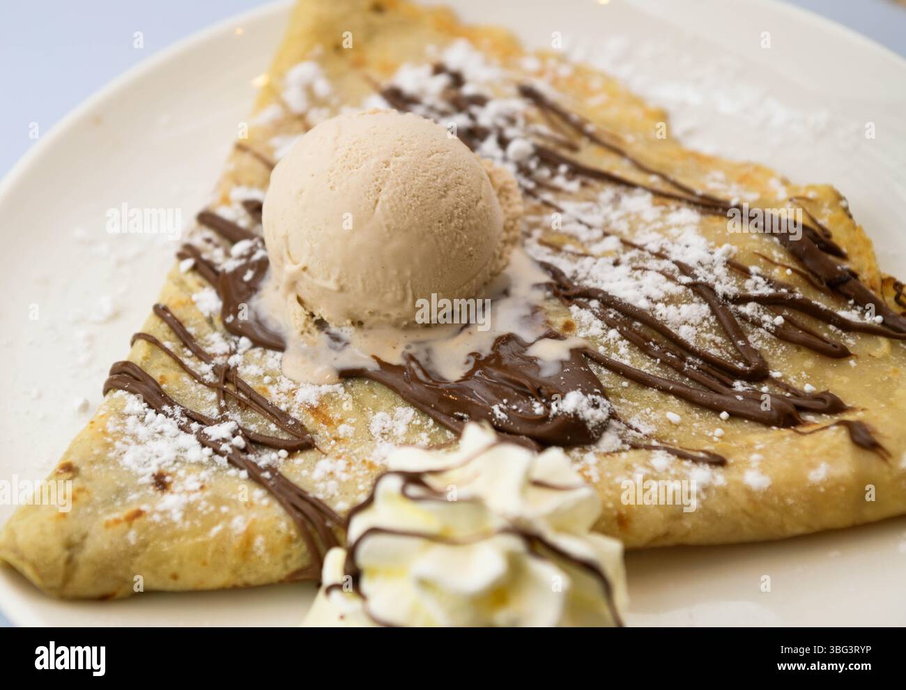Pfannkuchen mit Eis und Schokoladensauce auf einem weißen Teller Stockfoto