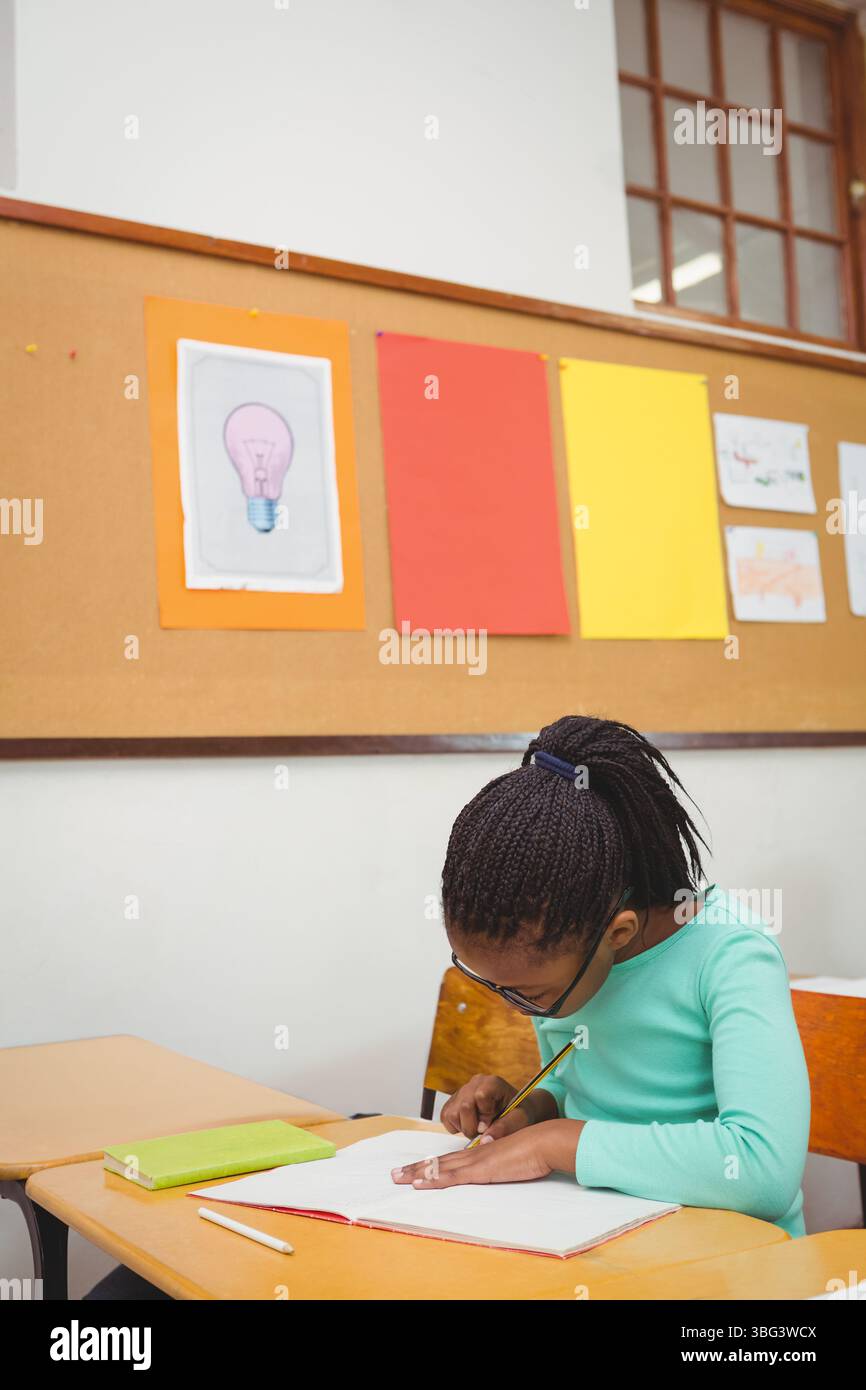 Das Notizbuch liegt auf dem Schreibtisch im Klassenzimmer, während der Bleistift auf dem grünen Buch in der Nähe des Fensters liegt Stockfoto
