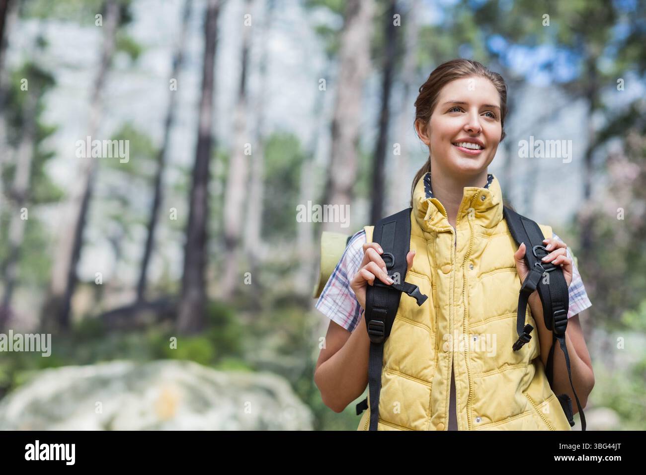 Weibliche Wanderer, die den Bergwaldpfad erkunden, trägt gelbe Weste und Rucksack mit Polster, Kopierraum Stockfoto