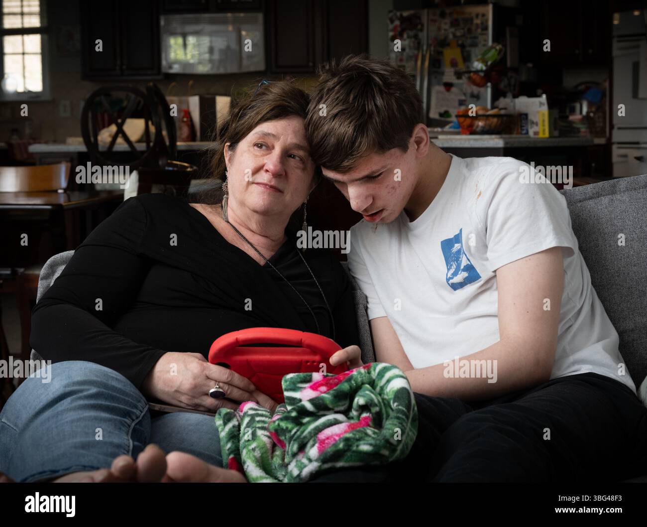 Fort Mill, South Carolina, USA. März 2025. BETH HODGES, alleinerziehende Mutter, mit ihrem 19-jährigen Sohn JACK, der eine seltene Krampfanfallsstörung namens Dravet-Syndrom sowie Autismus der Stufe 3 hat. "Er hat die Bedürfnisse eines Kleinkindes in einem männlichen Körper", erklärt sie. Wagenheber erfordert 24/7 Pflege. Beth plant, den Staat zu verlassen, sobald Jack mit 21 Jahren aus dem Bildungssystem des Staates gealtert ist. "Hier ist nichts für ihn," sagte sie. (Kreditbild: © Robin Rayne/ZUMA Press Wire) NUR REDAKTIONELLE VERWENDUNG! Nicht für kommerzielle ZWECKE! Stockfoto