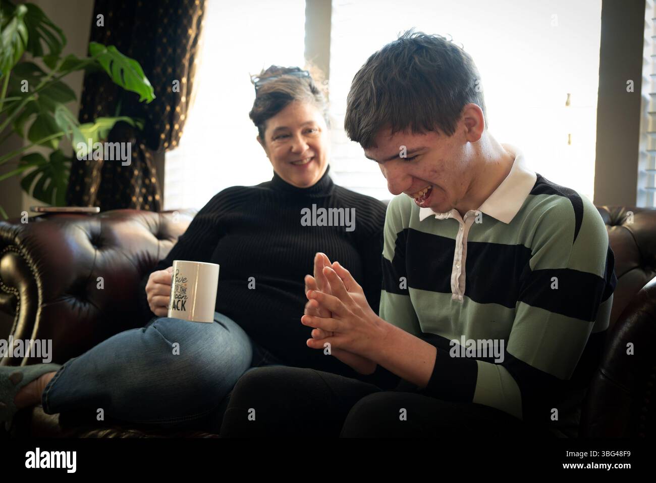 Ft. Mill, South Carolina, USA. März 2025. BETH HODGES genießt „Kaffeezeit“ mit ihrem 19-jährigen Sohn Jack, während sie auf einen Bus zu einer speziellen Schule für Kinder mit Entwicklungsbehinderungen warten. Jack hat eine seltene Krampfanfallsstörung namens Dravet-Syndrom, die seit der Geburt auftritt und häufige, unvorhersehbare Krampfanfälle verursacht, die zwischen 15 Sekunden und Minuten dauern. Er hat Autismus der Stufe 3, das schwerste Ende des Spektrums, das umfassende, rund um die Uhr versorgte Versorgung erfordert. (Kreditbild: © Robin Rayne/ZUMA Press Wire) NUR REDAKTIONELLE VERWENDUNG! Nicht für kommerzielle ZWECKE! Stockfoto