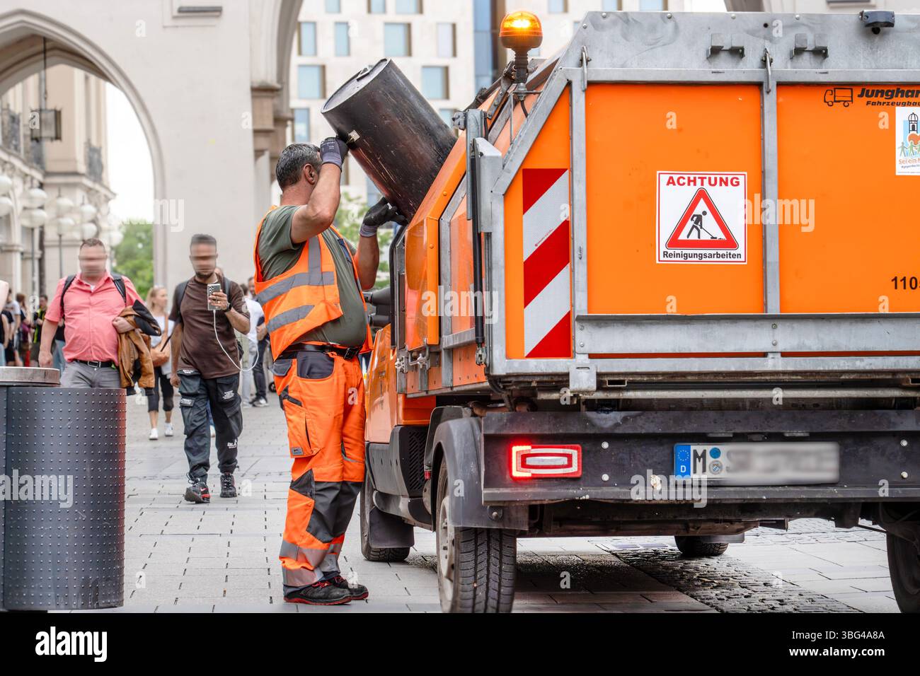 Mitarbeiter der Straßenreinigung leert die Abfallbehälter in der Fußgängerzone, München, Juni 2025 Deutschland, München, Juni 2025, Mitarbeiter der Straßenreinigung der Stadt München leert die Abfallbehälter in der Fußgängerzone, Nähe Karlstor, Leerung der Mülleimer, körperliche Arbeit, Sauberkeit in der Innenstadt, orangenes Müllfahrzeug, Abfall, Müll, Bayern *** Straßenreinigungsangestellter leert die Mülltonnen in der Fußgängerzone, München, Juni 2025 Deutschland, München, Juni 2025, der Straßenreinigungsangestellte der Stadt München entleert die Mülltonnen in der Fußgängerzone bei Karlsto Stockfoto