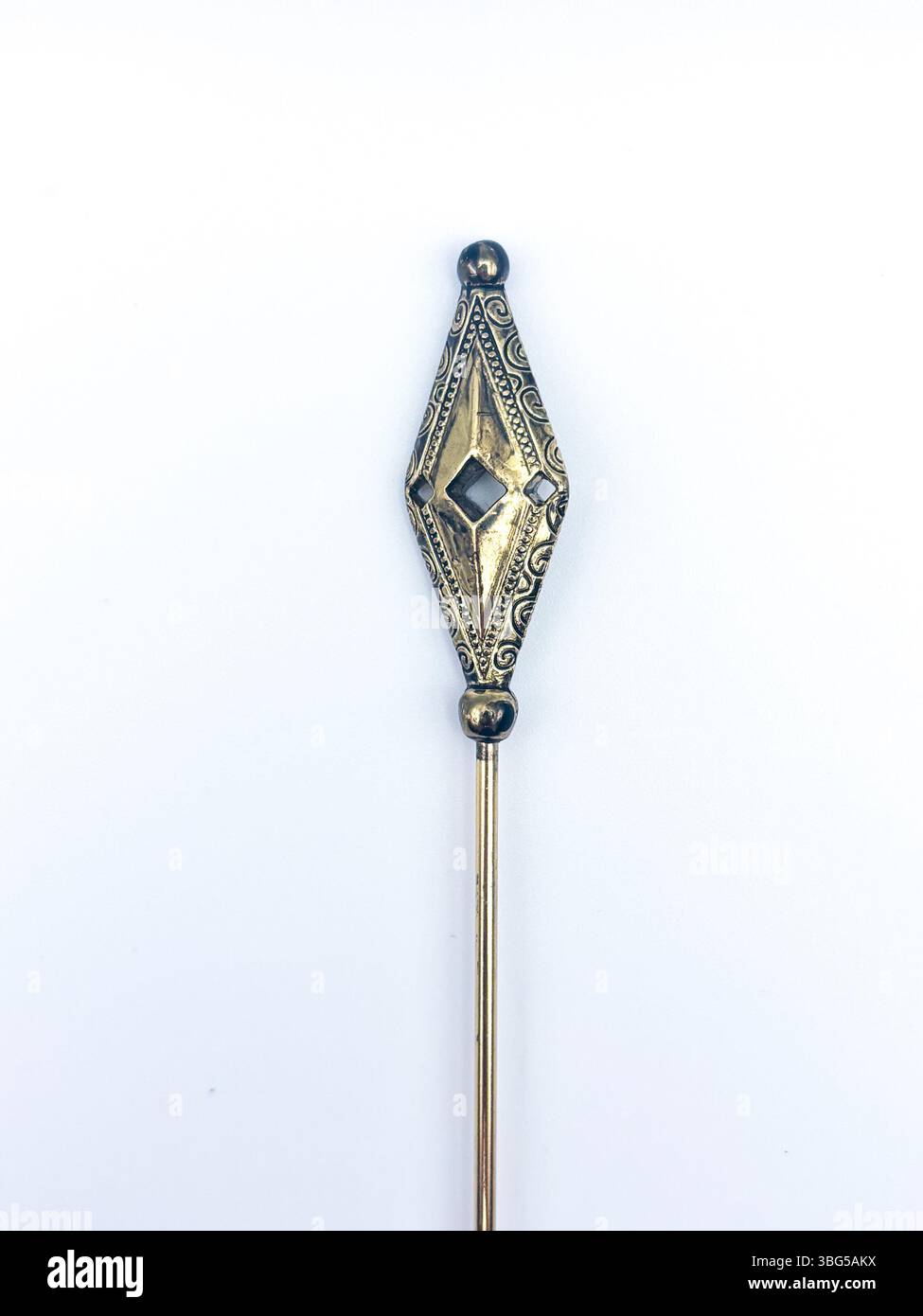 Eine geometrische Hutnadel in Vintage-Gold mit filigranen und ausgeschnittenen Details vor weißem Hintergrund. Auch als Stielstift bezeichnet. Stockfoto