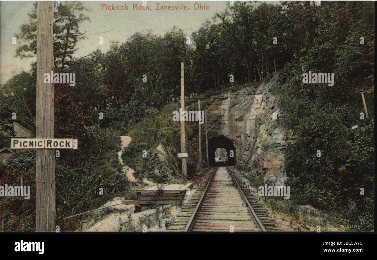 Dieses kolorierte Foto aus dem Jahr 1910 zeigt Picnic Rock in Zanesville, Ohio, mit Überlandspuren, die durch einen Tunnel an der Seite des Felshügels führen. Das Bild fängt die natürliche Schönheit der Gegend zusammen mit der Transportinfrastruktur des frühen 20. Jahrhunderts ein. Stockfoto