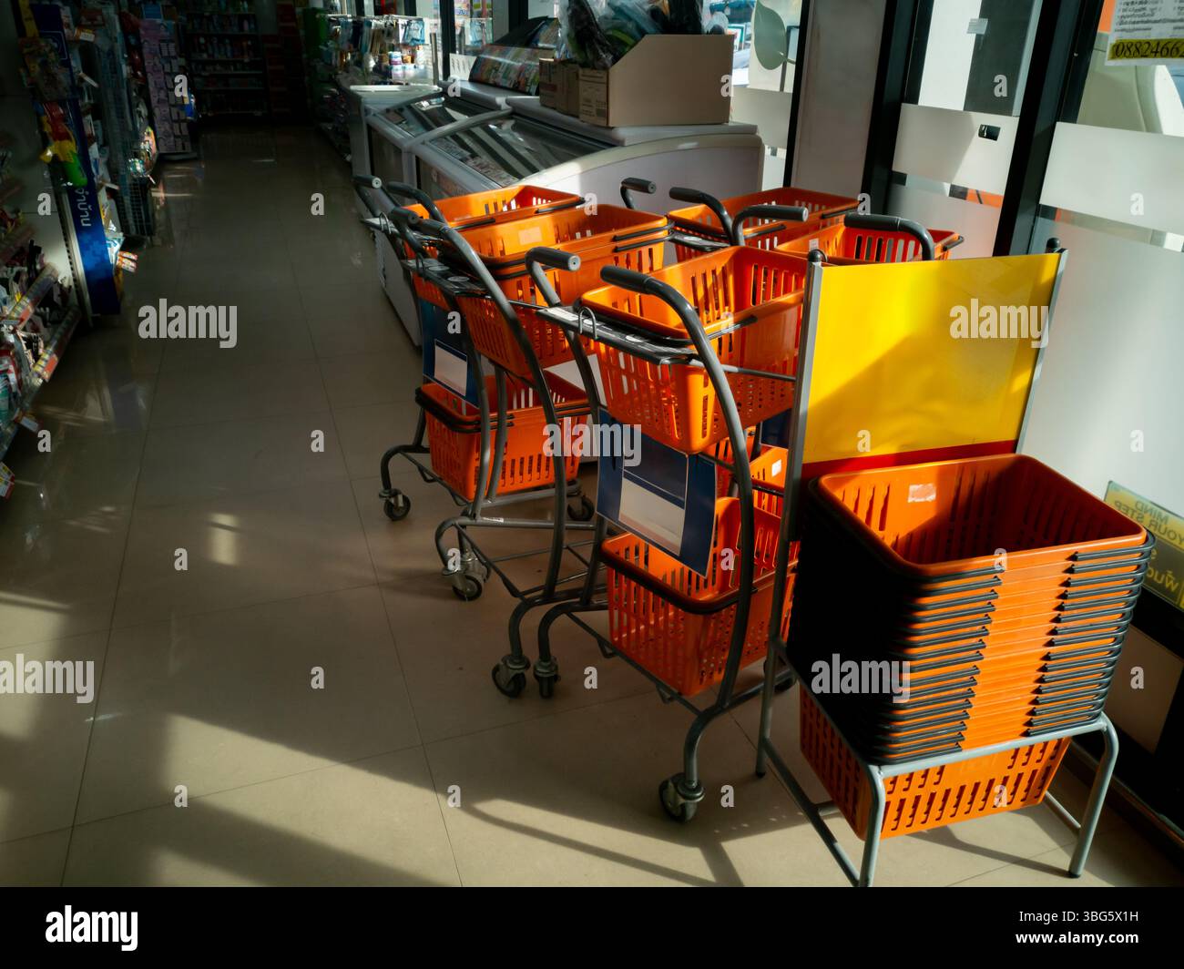 Ein lebhafter Verkaufsbereich mit Einkaufswagen und Körben in Orange und Grau. Die helle Inneneinrichtung bietet eine einladende Umgebung für Käufer. Stockfoto