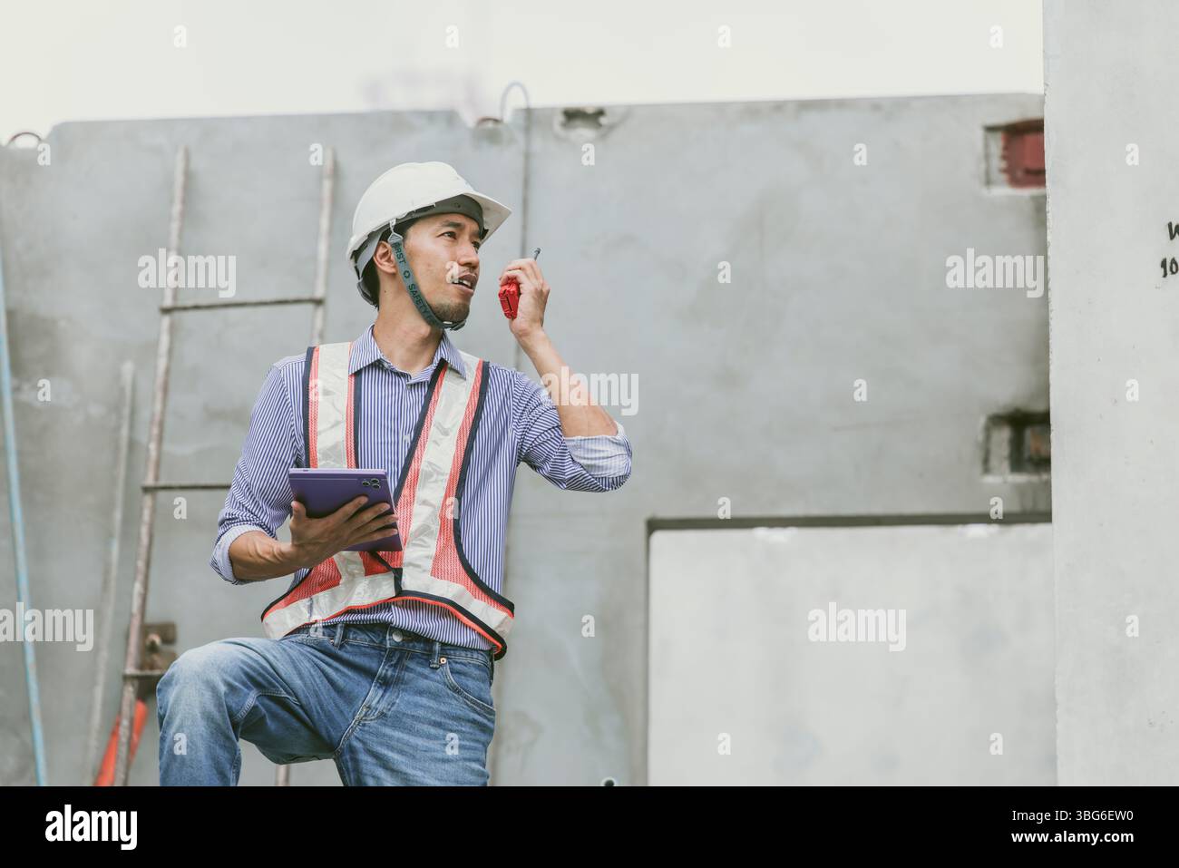 Asiatischer Ingenieur leitet Bauprojekt auf der Baustelle, professioneller Baumeister überwacht den Entwicklungsprozess Stockfoto