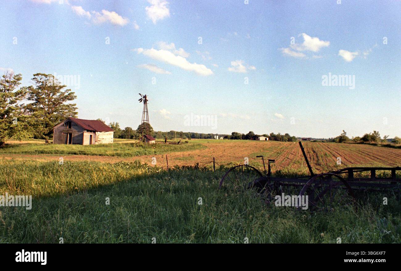 Foto von A.V. Shirk von einer Farm in der Nähe von Galion, Ohio, mit einer alten Scheune und Windmühle. Shirk, geboren 1938, war ein gebürtiger Ohio, der später für seine Fotografie bekannt wurde. Er arbeitete bei der WOSU, wo er viele Volksmusik und Protestkonzerte aufnahm. Seine Arbeiten konzentrierten sich oft auf Alltagsszenen und ländliche Landschaften. Stockfoto