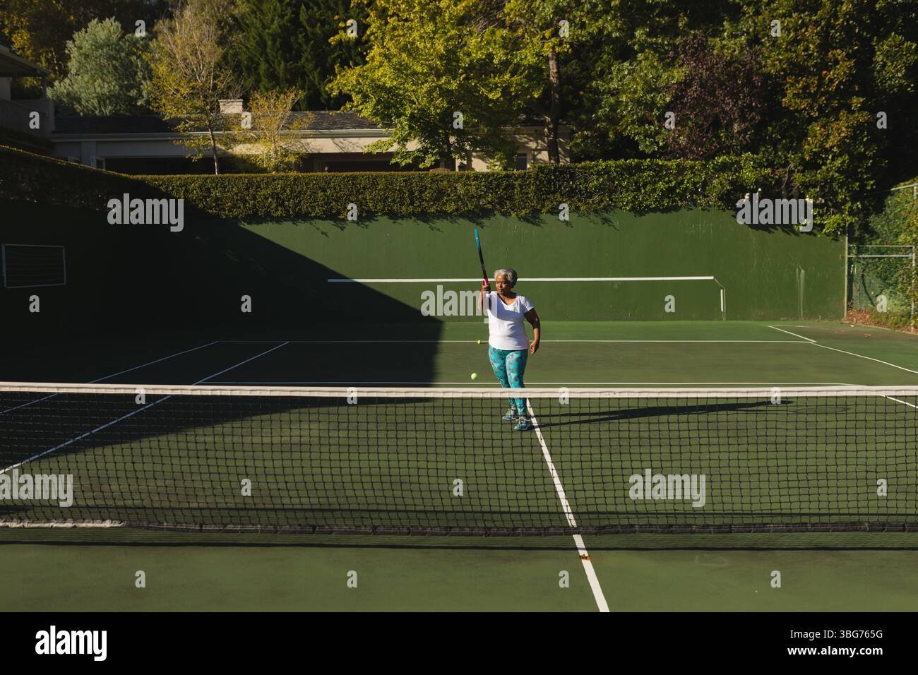 Ältere Afroamerikanerin in Sportkleidung, die sich auf den Tennisball vorbereitet Stockfoto