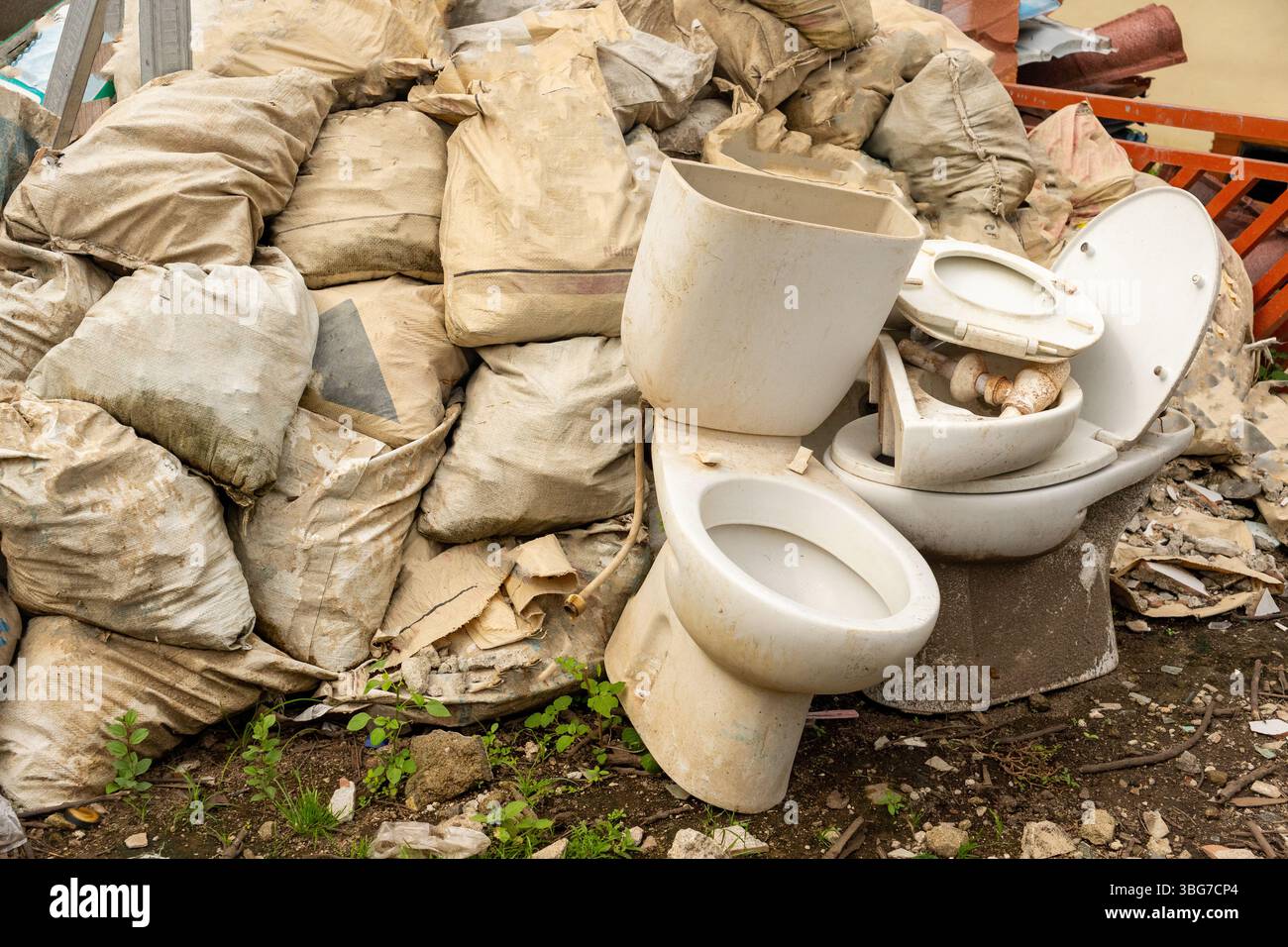 Ein Müllhaufen mit einer Toilette drauf. Die Toilette ist kaputt und hat einen weißen Deckel Stockfoto