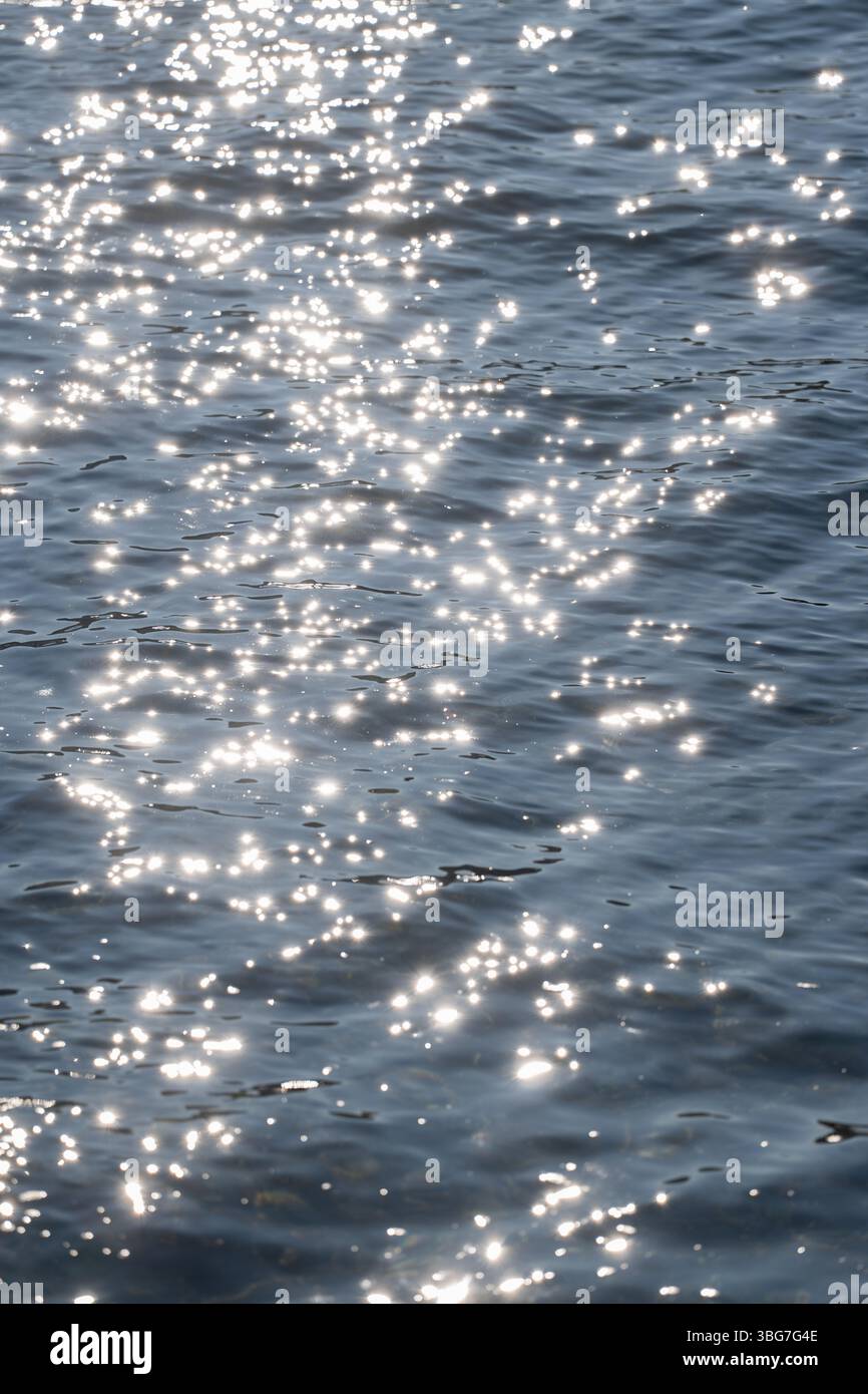 Sonnenlicht reflektiert und funkelt auf einer blauen Wasseroberfläche Stockfoto