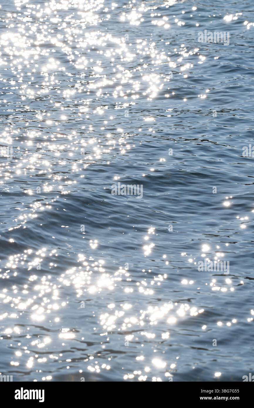 Sonnenlicht reflektiert und glitzert auf einer sich sanft bewegenden Wasseroberfläche Stockfoto