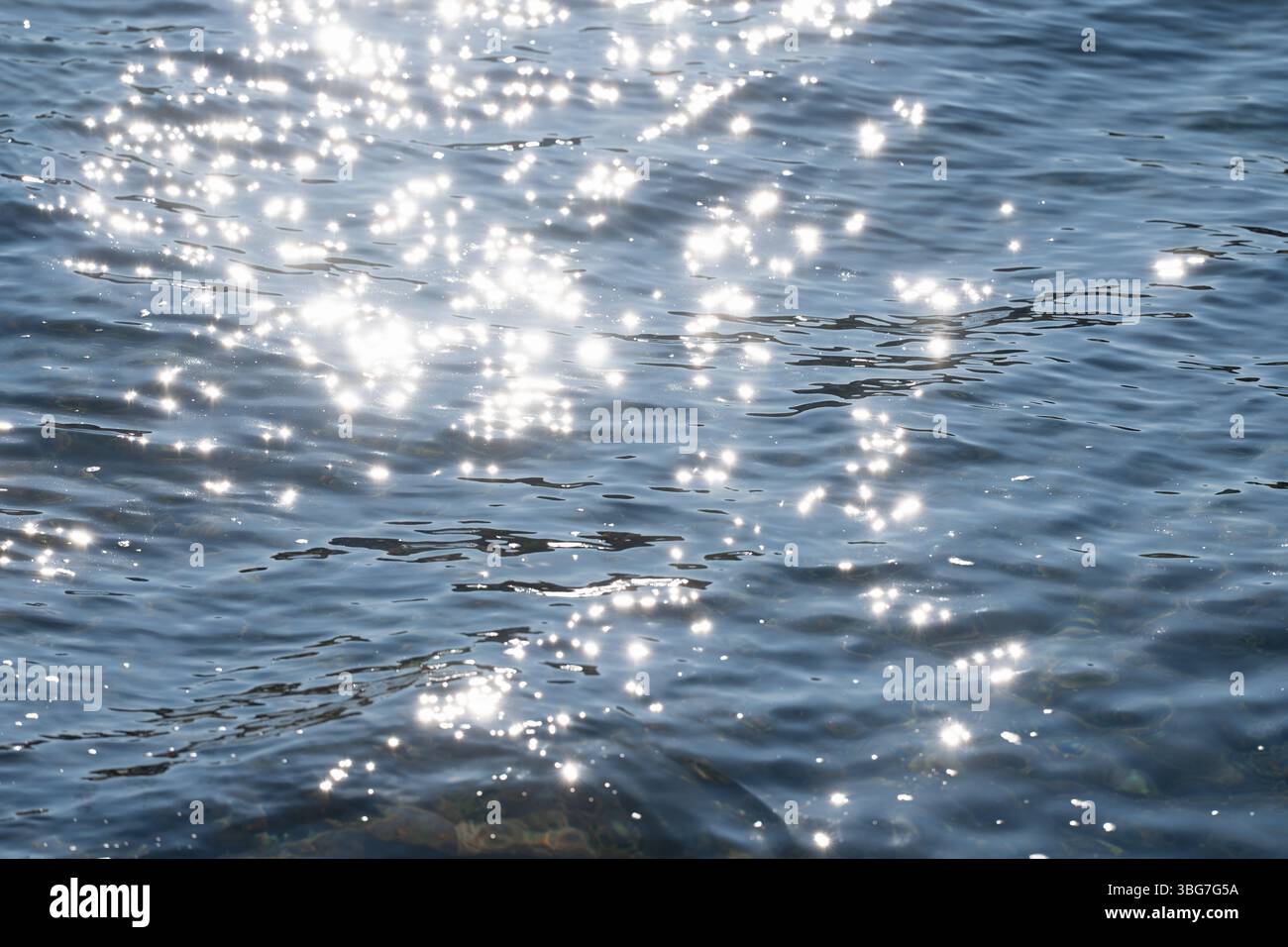 Sonnenlicht erzeugt funkelnde Reflexionen auf der Oberfläche des sanft plätschernden Wassers Stockfoto