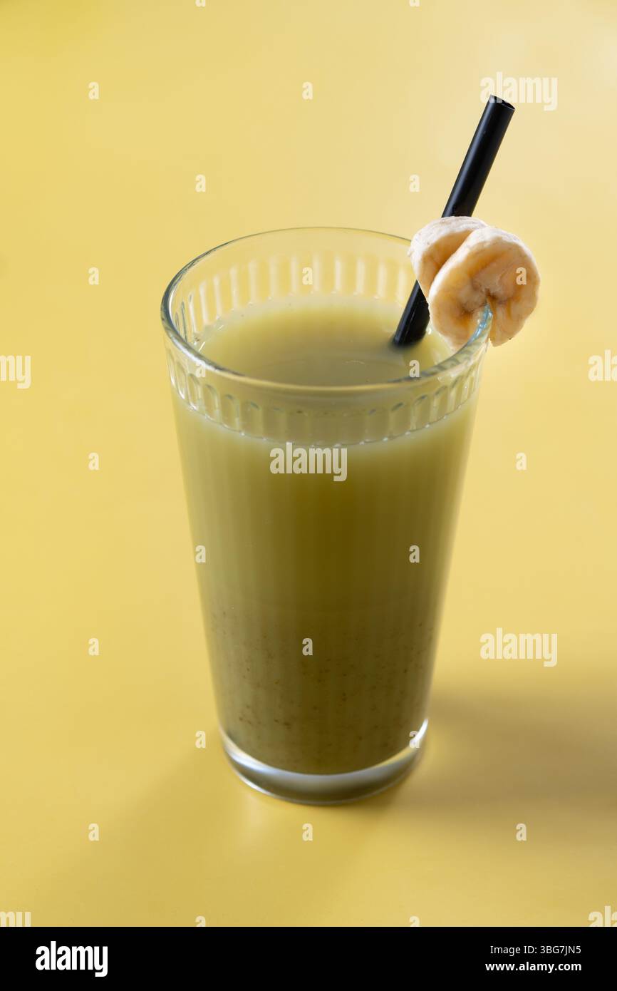 Grüner Smoothie mit Spinat, Banane, Apfel und Zitrone auf gelbem Hintergrund Stockfoto