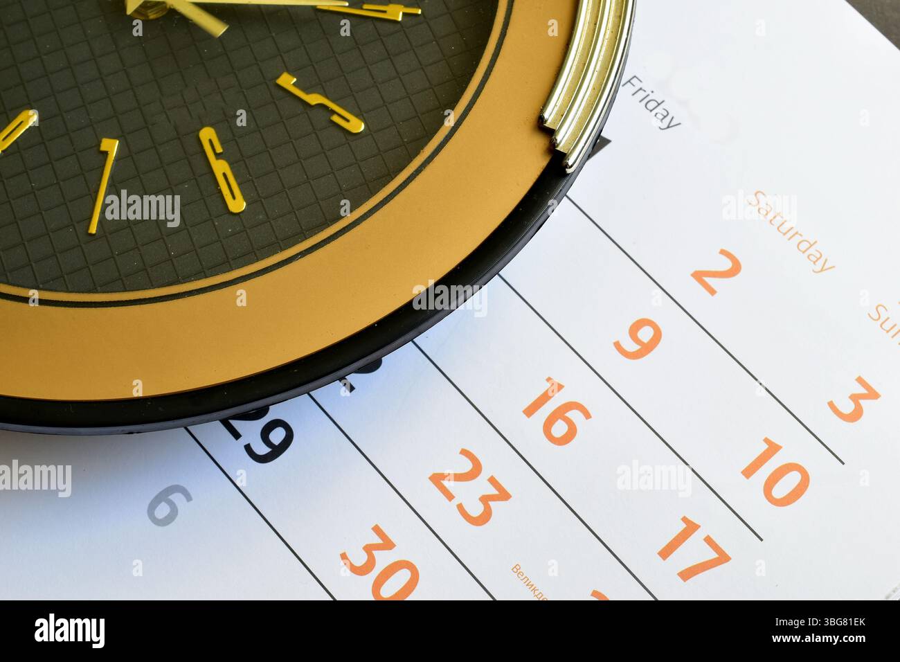 Nahaufnahme eines Zifferblatts und eines Wandkalenders mit Datumsangaben für Tage und Wochen. Stockfoto