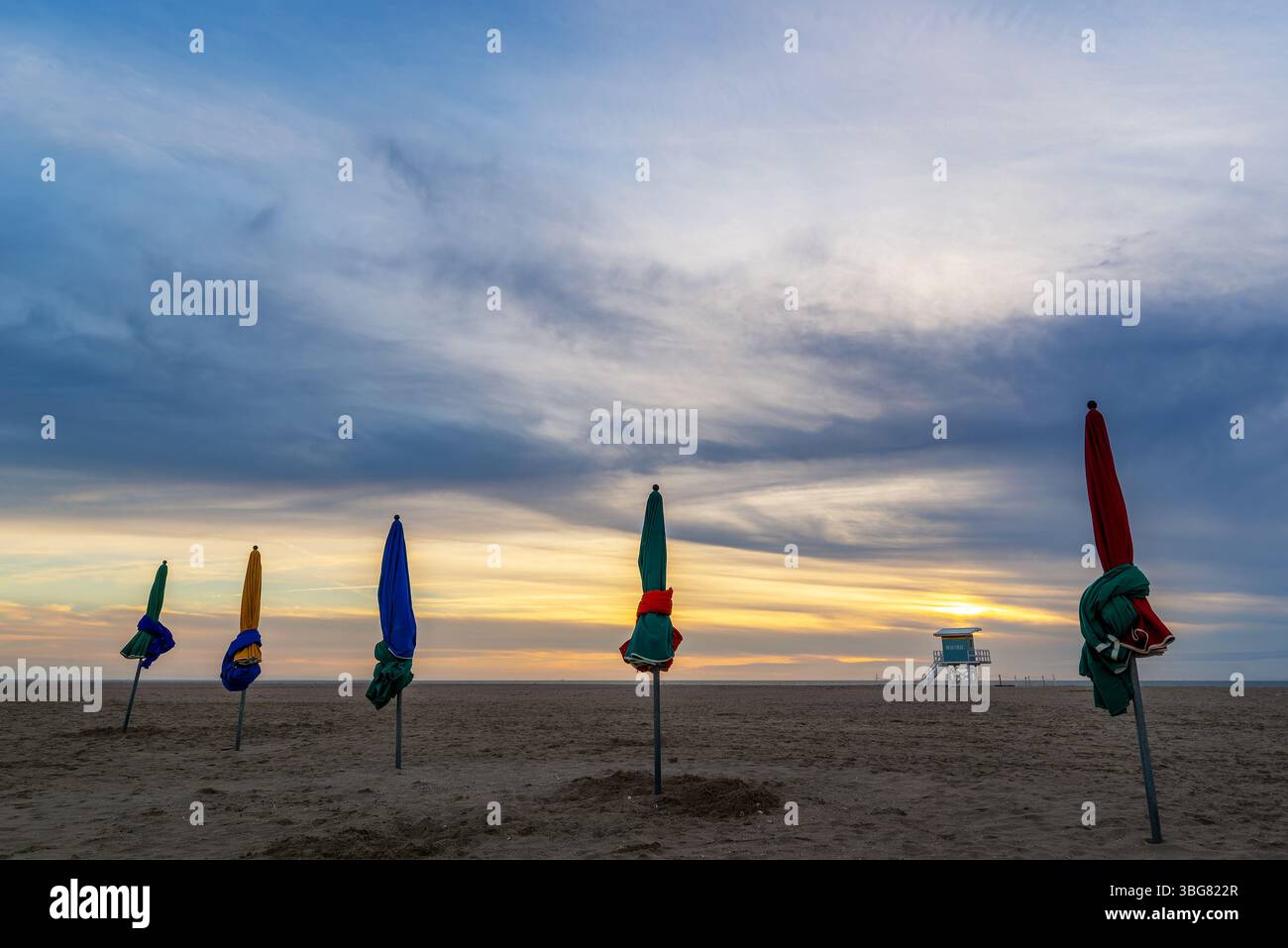 Strand von Deauville bei Sonnenuntergang, berühmte Vintage-Sonnenschirme und Rettungsschwimmer-Stationsturm, in der Normandie, Frankreich Stockfoto