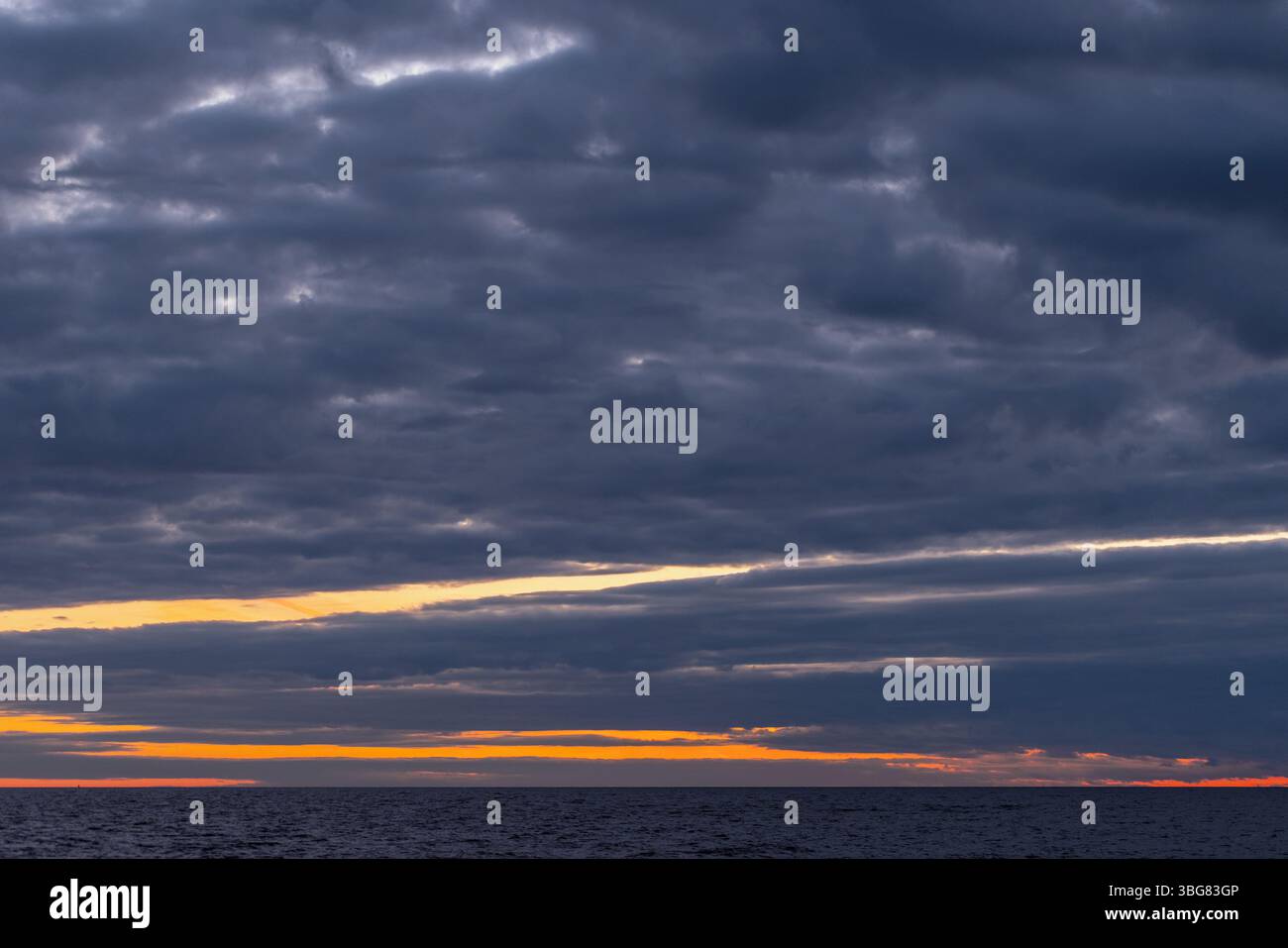 Foto der Küstenlandschaft mit dunklem, bewölktem Himmel über dem Horizont bei Sonnenuntergang Stockfoto