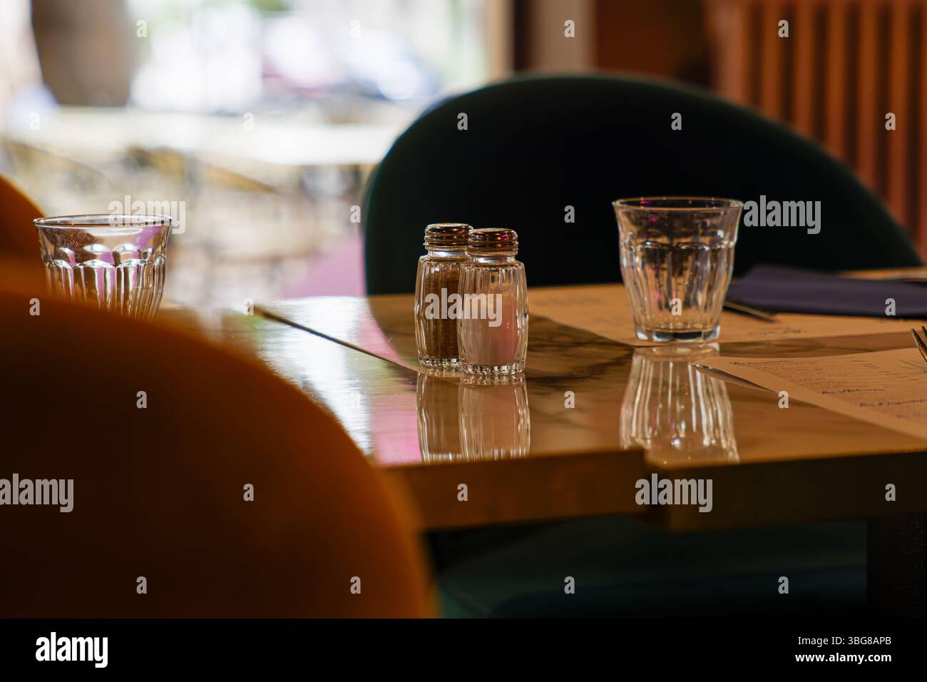 Gemütlicher Kaffeetisch mit Salz- und Pfefferstreuern, Gläsern und Menüs. Stockfoto