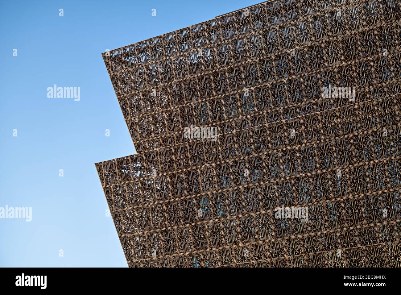 WASHINGTON DC – Detail der markanten bronzefarbenen, gemusterten Metalltafeln, die das „Corona“-Äußere des Smithsonian National Museum of African American History and Culture in der National Mall bilden. Diese perforierten Aluminiumplatten wurden vom führenden Architekten David Adjaye entworfen und sind von den ornamentalen Eisenarbeiten inspiriert, die von versklavten afroamerikanischen Handwerkern im Süden geschaffen wurden. Das Museum, das im September 2016 eröffnet wurde, verfügt über 3.600 dieser dekorativen Tafeln, die gefiltertes Licht hereinlassen und gleichzeitig Schatten für die Innenräume bieten. Stockfoto